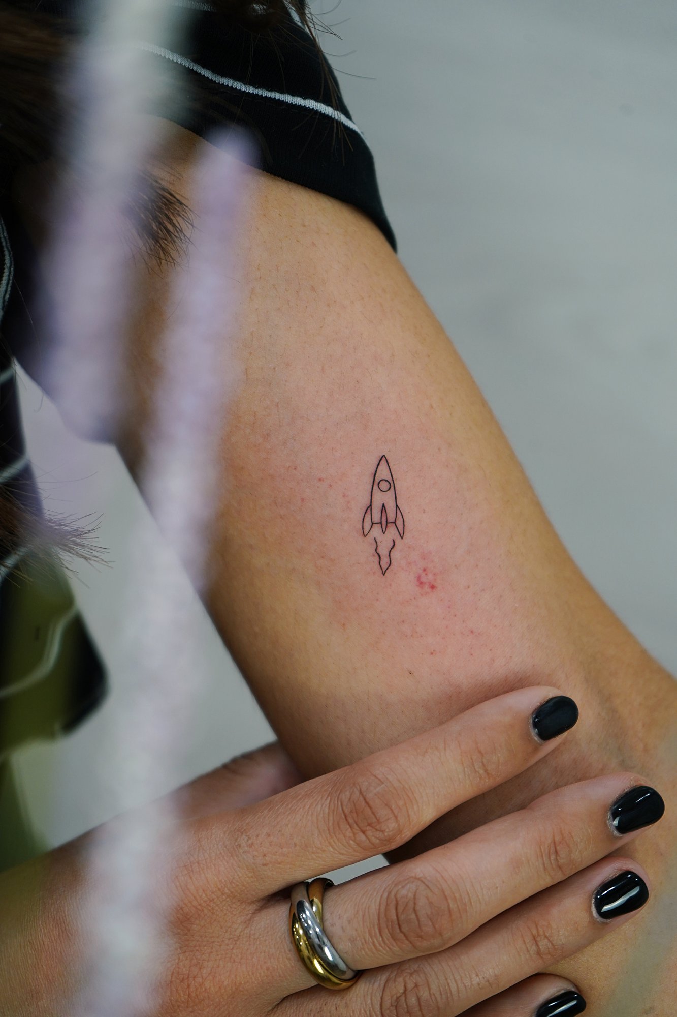 Tatuaje de cohete en biceps, línea fina