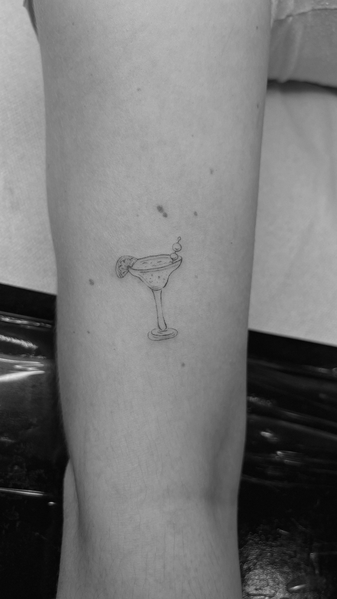 Tatuaje de copa coctel margarita garnish en antebrazo, línea fina