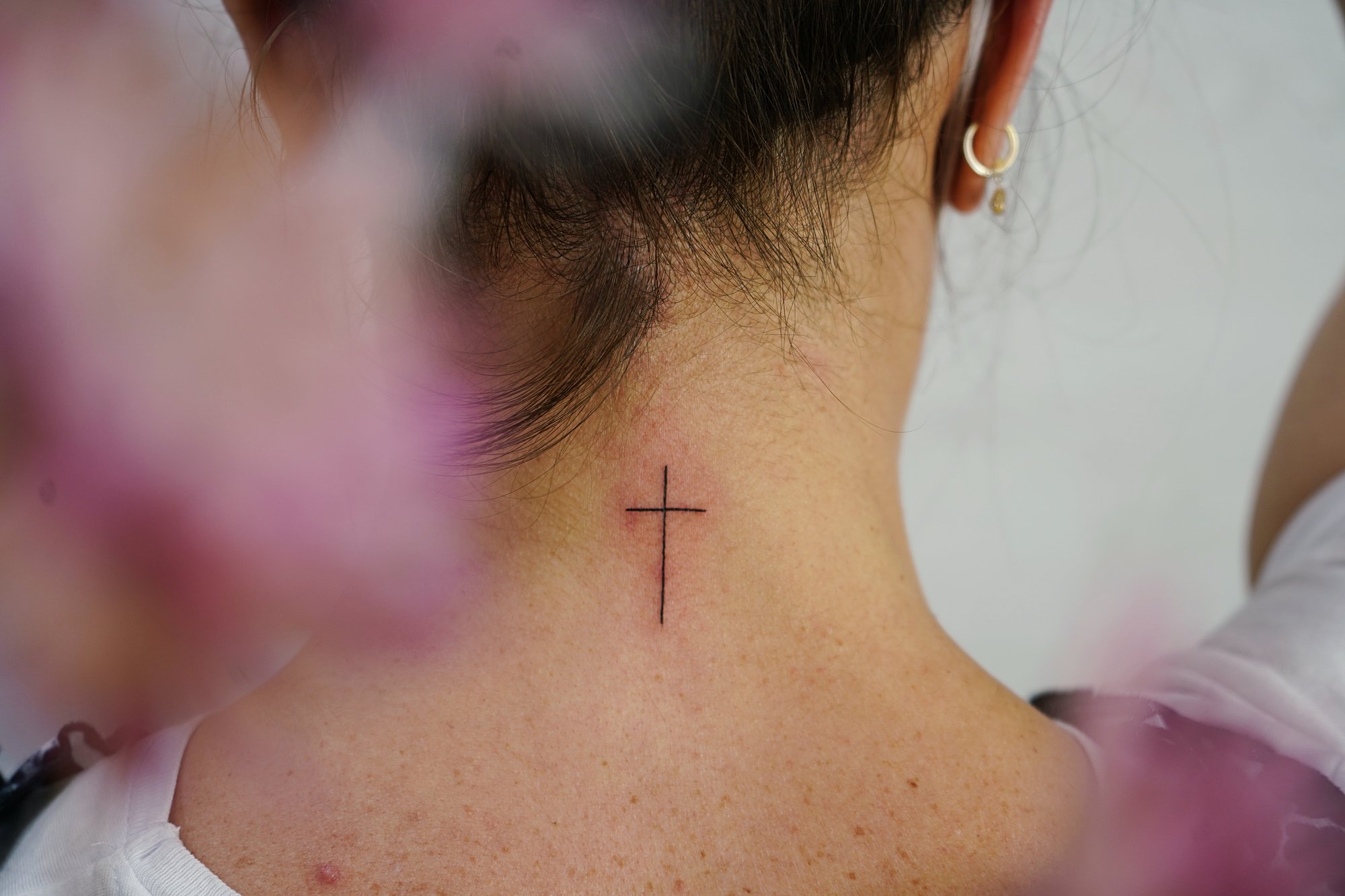 Tatuaje de cruz religiosa en nuca, línea fina