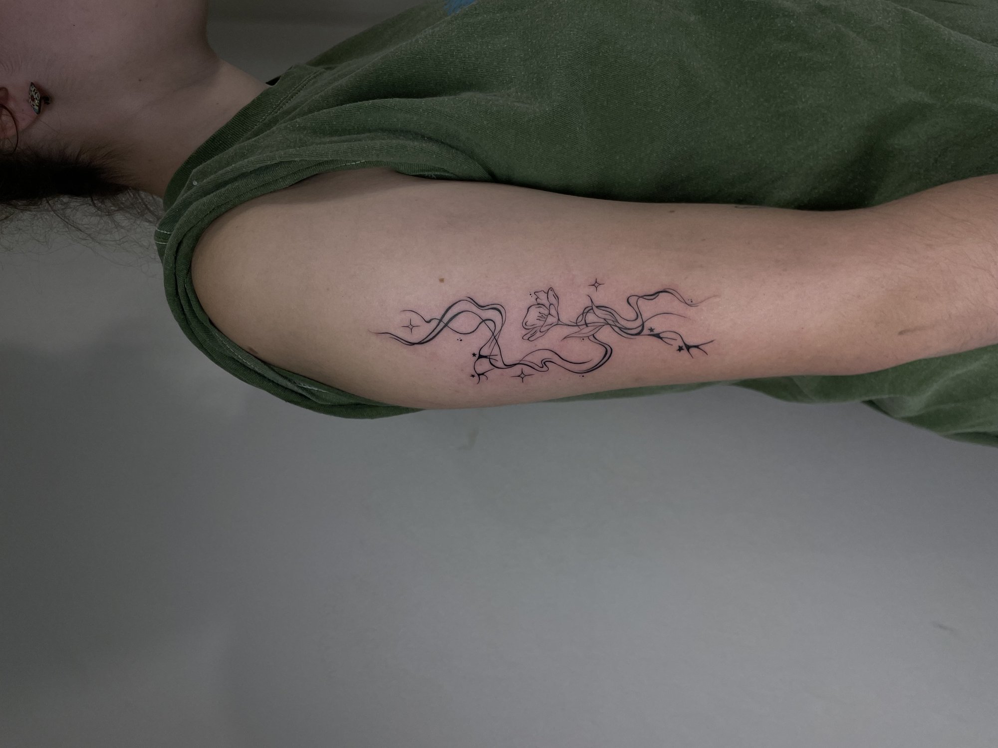 Tatuaje de lineas fluidas flor estrellas en brazo, línea fina