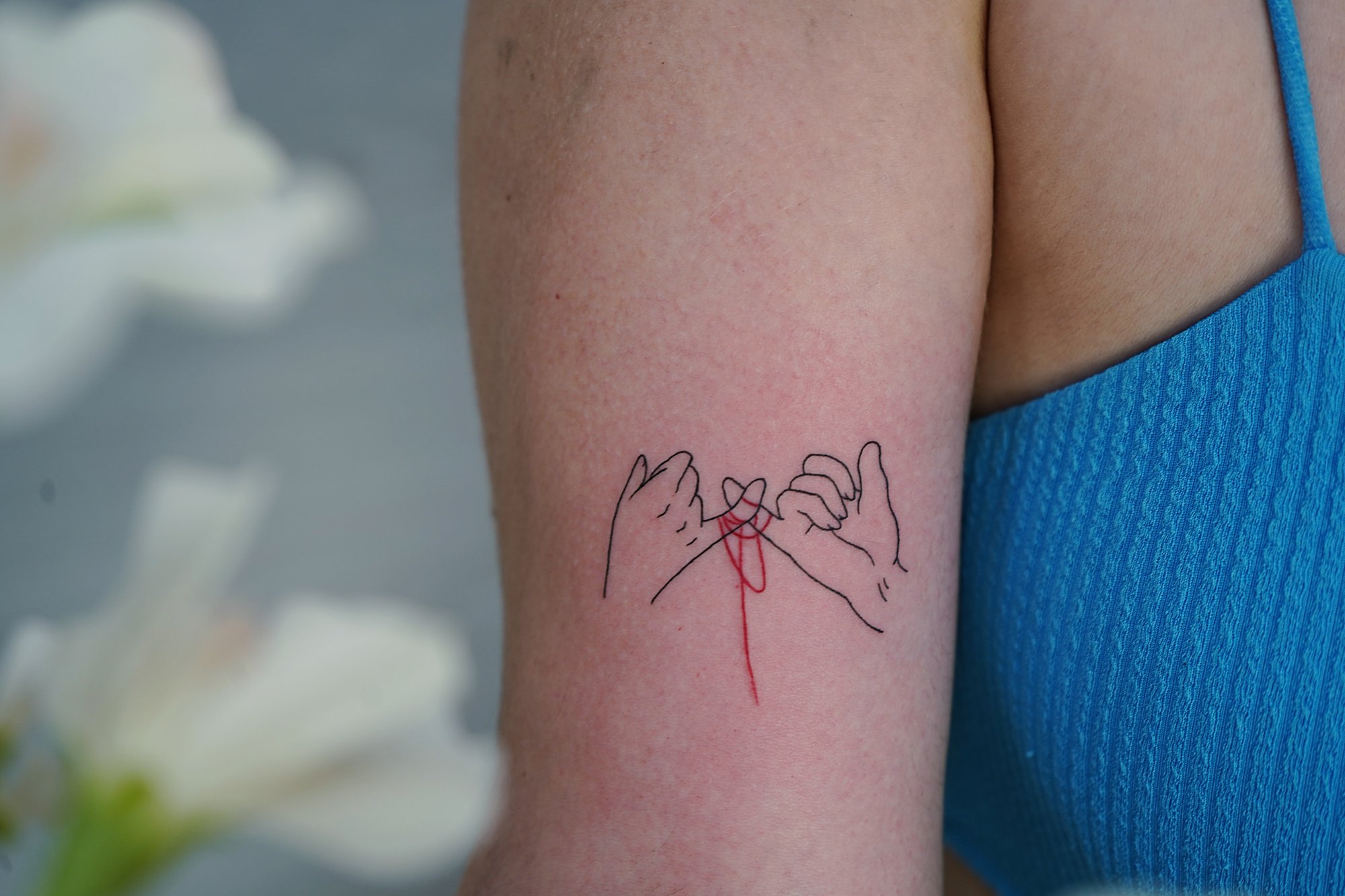 Tatuaje de logos manos en biceps, línea fina