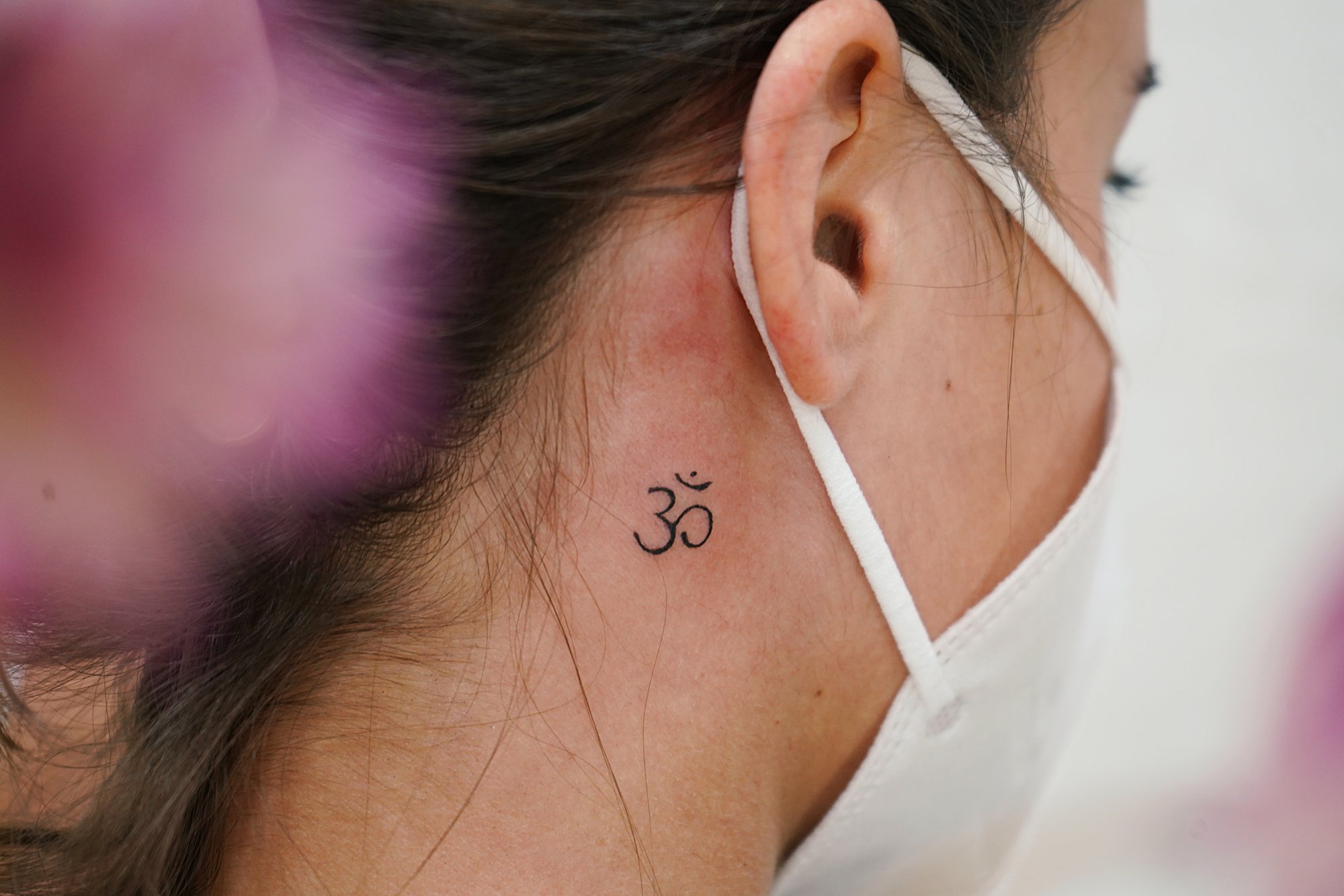 Tatuaje de om en detras oreja, línea fina