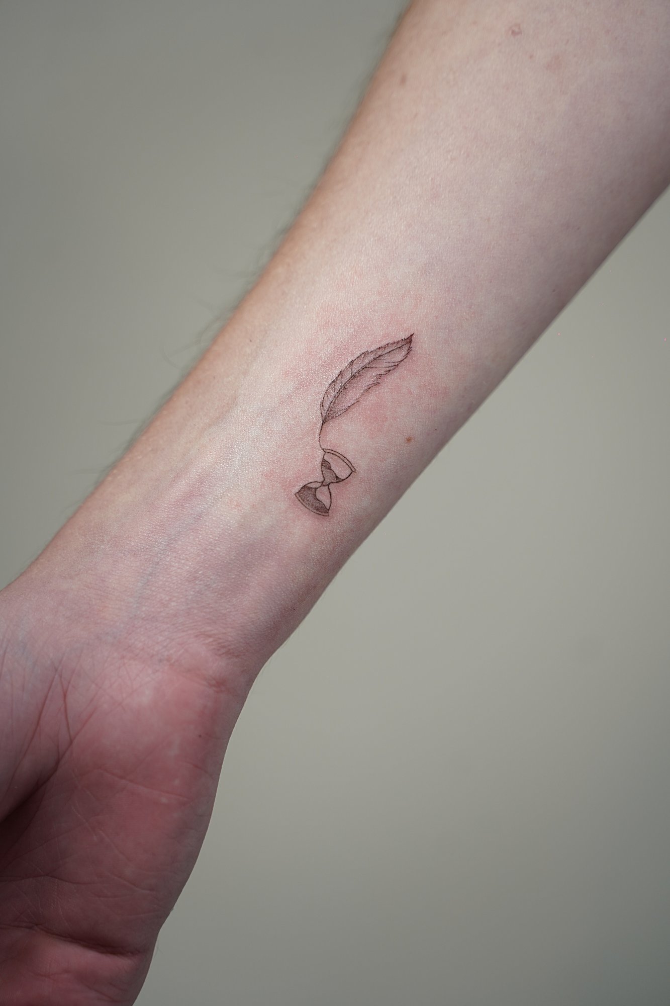 Tatuaje de pluma reloj arena en zona desconocida, línea fina