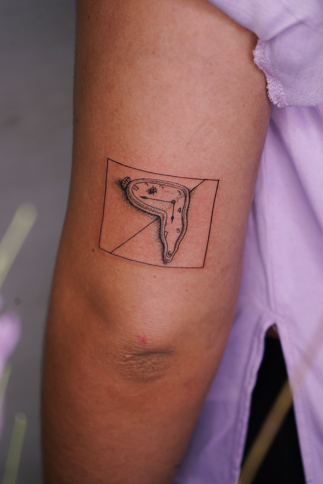 Tatuaje de reloj derretido en codo, línea fina