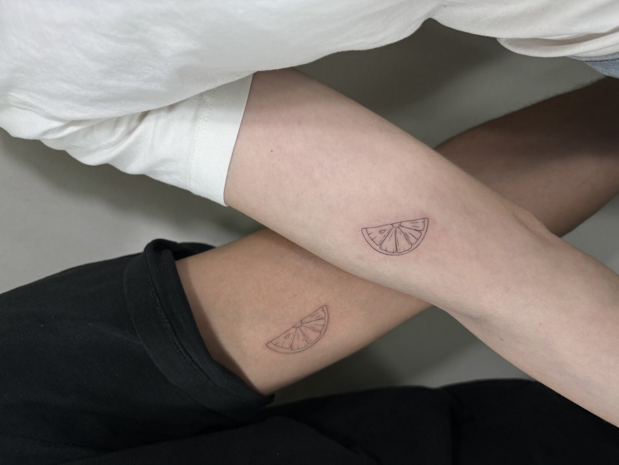 Tatuaje de rodaja de citrico matching en antebrazo, línea fina