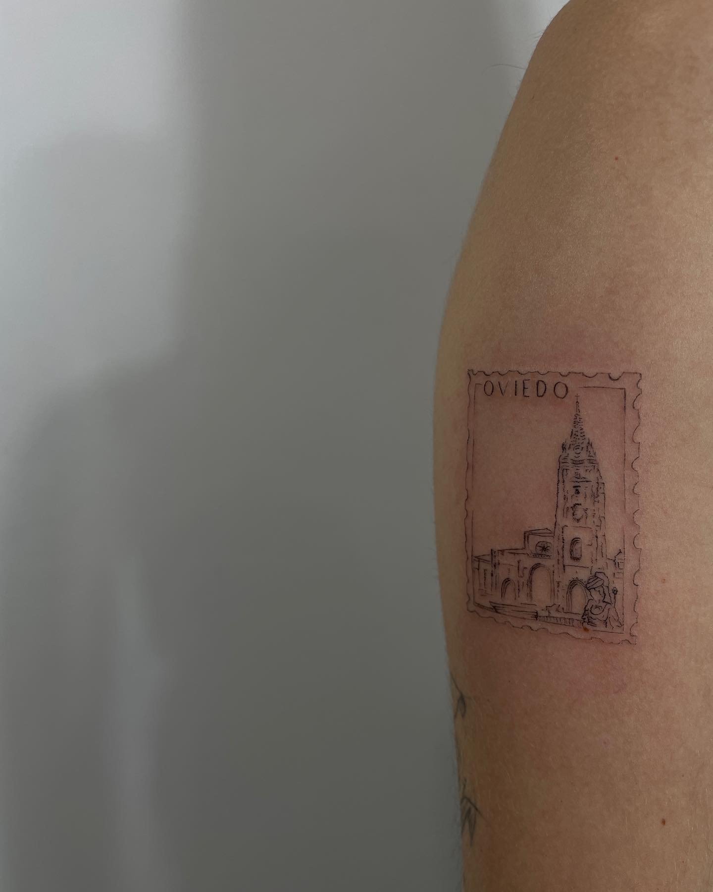 Tatuaje de sello postal catedral oviedo en brazo, línea fina