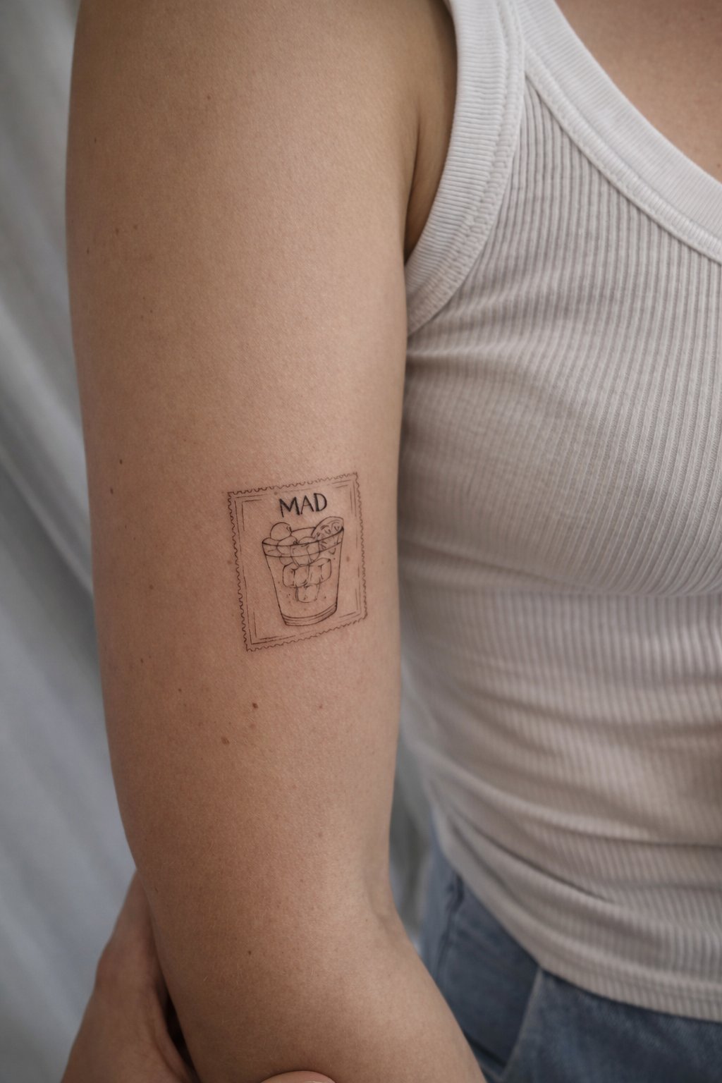Tatuaje de sello postal vaso mad en brazo, línea fina