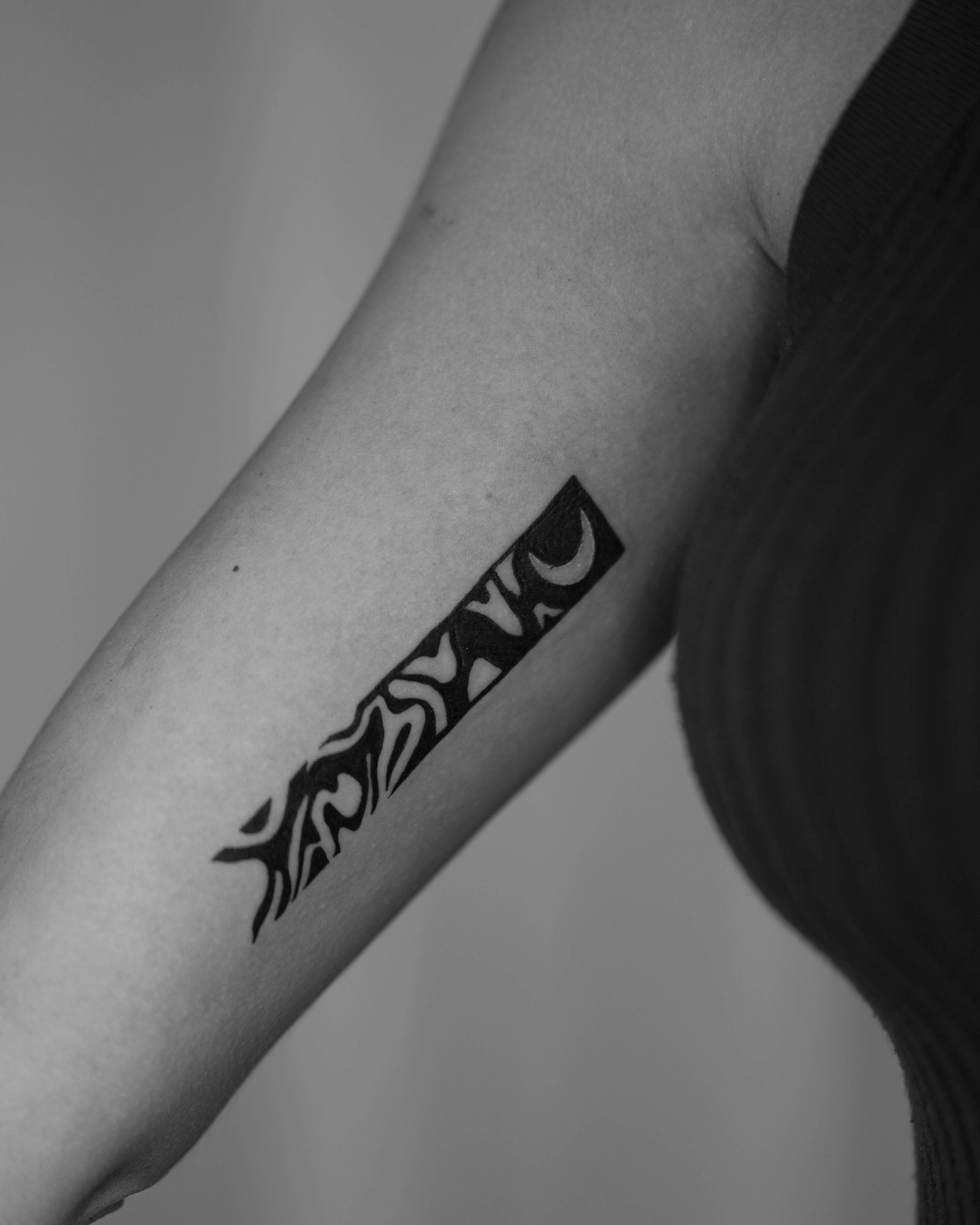 Tatuaje de tribal diagonal con luna en antebrazo, línea fina