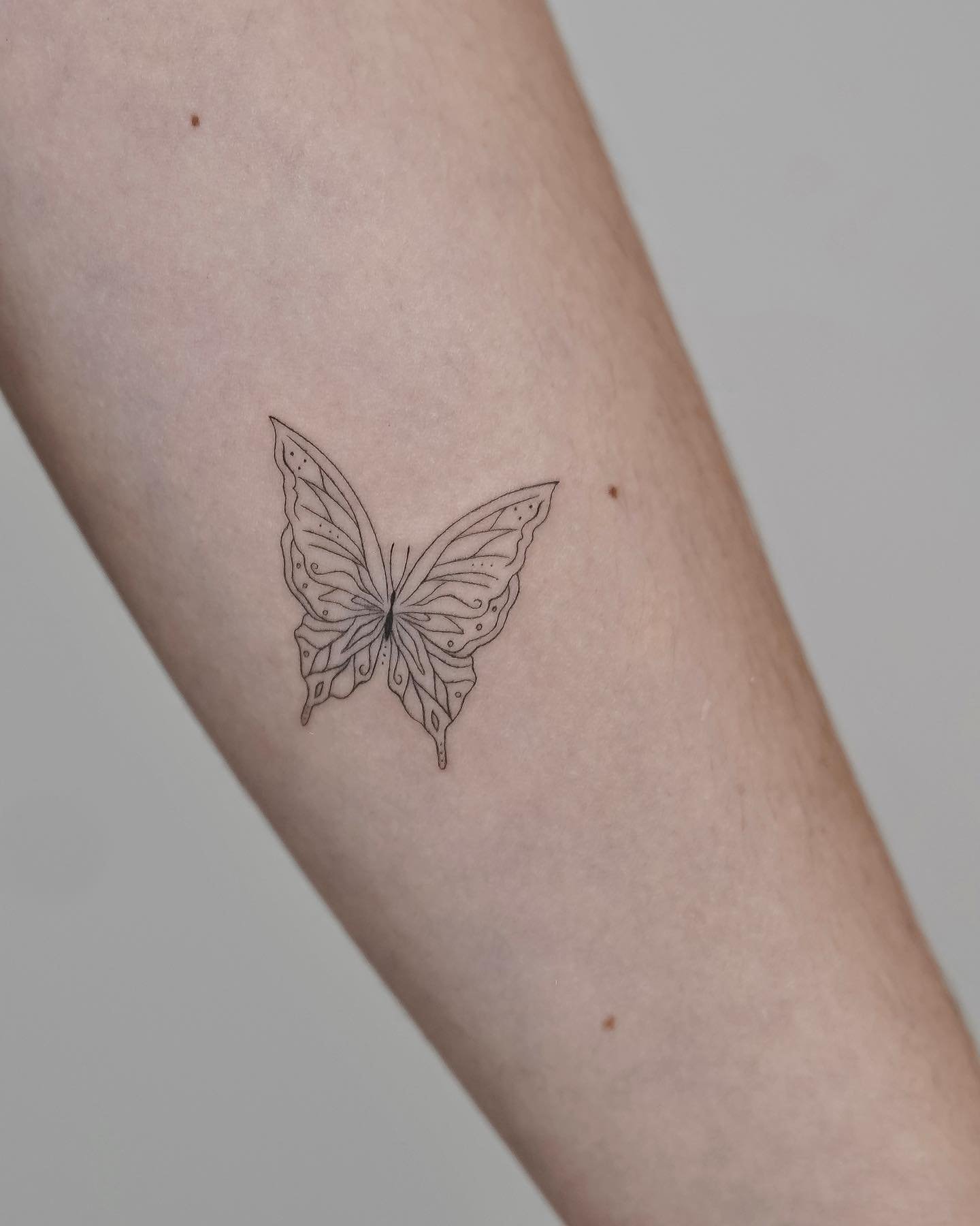 Tatuaje de mariposa en antebrazo, línea fina Sinkply Madrid