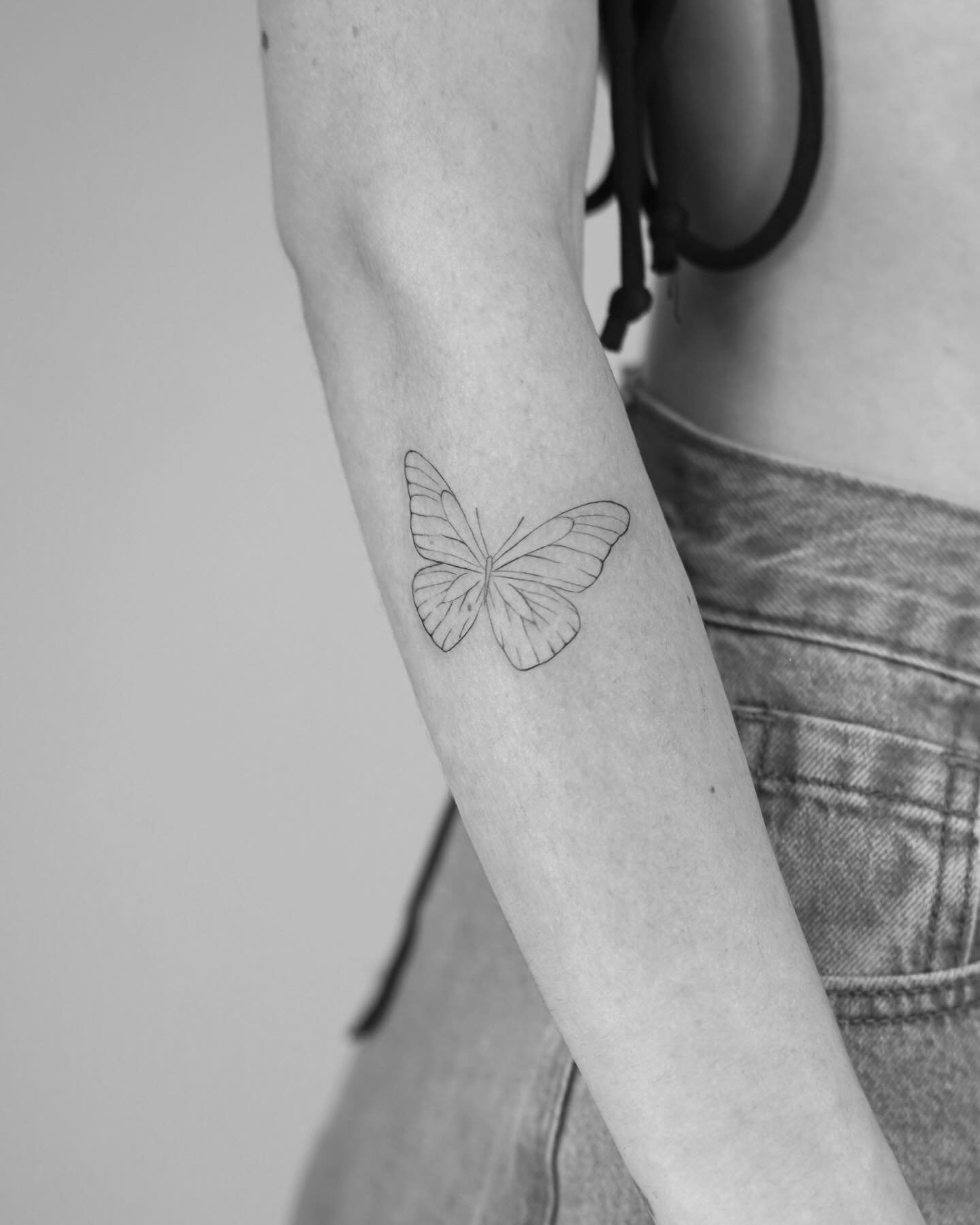 Tatuaje de mariposa en antebrazo, línea fina Sinkply Madrid