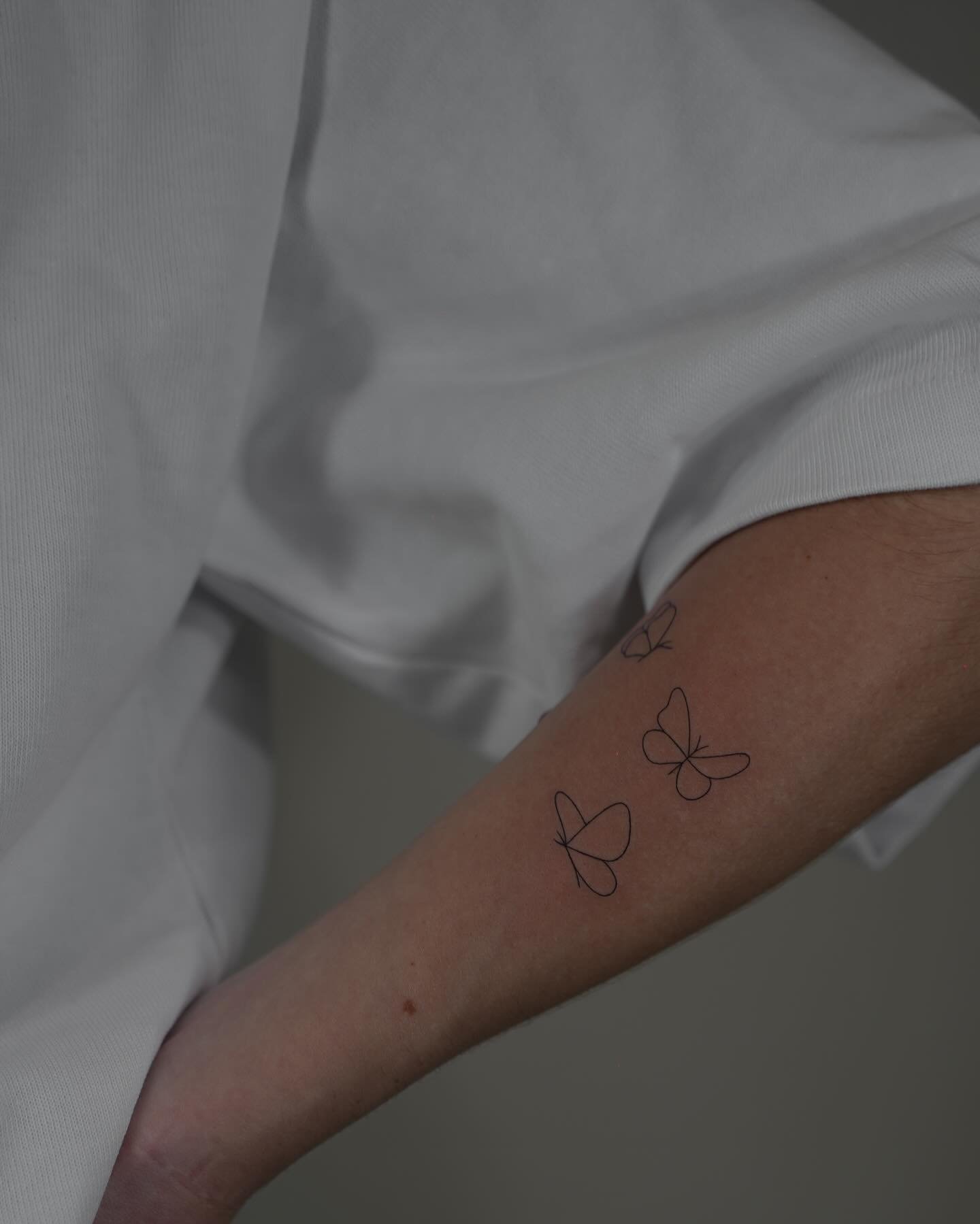 Tatuaje de mariposa en antebrazo, línea fina Sinkply Madrid