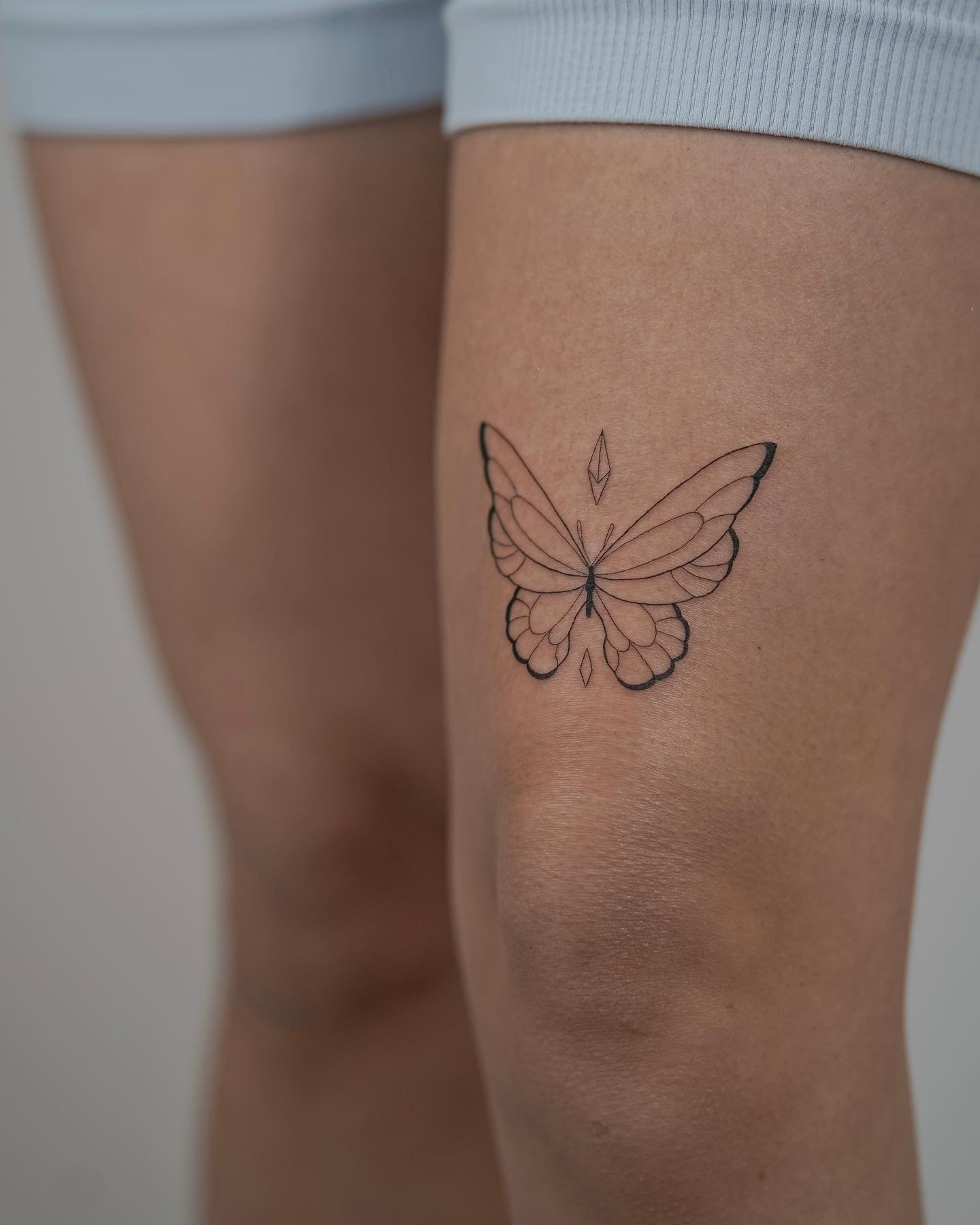 Tatuaje de mariposa en muslo, línea fina Sinkply Madrid