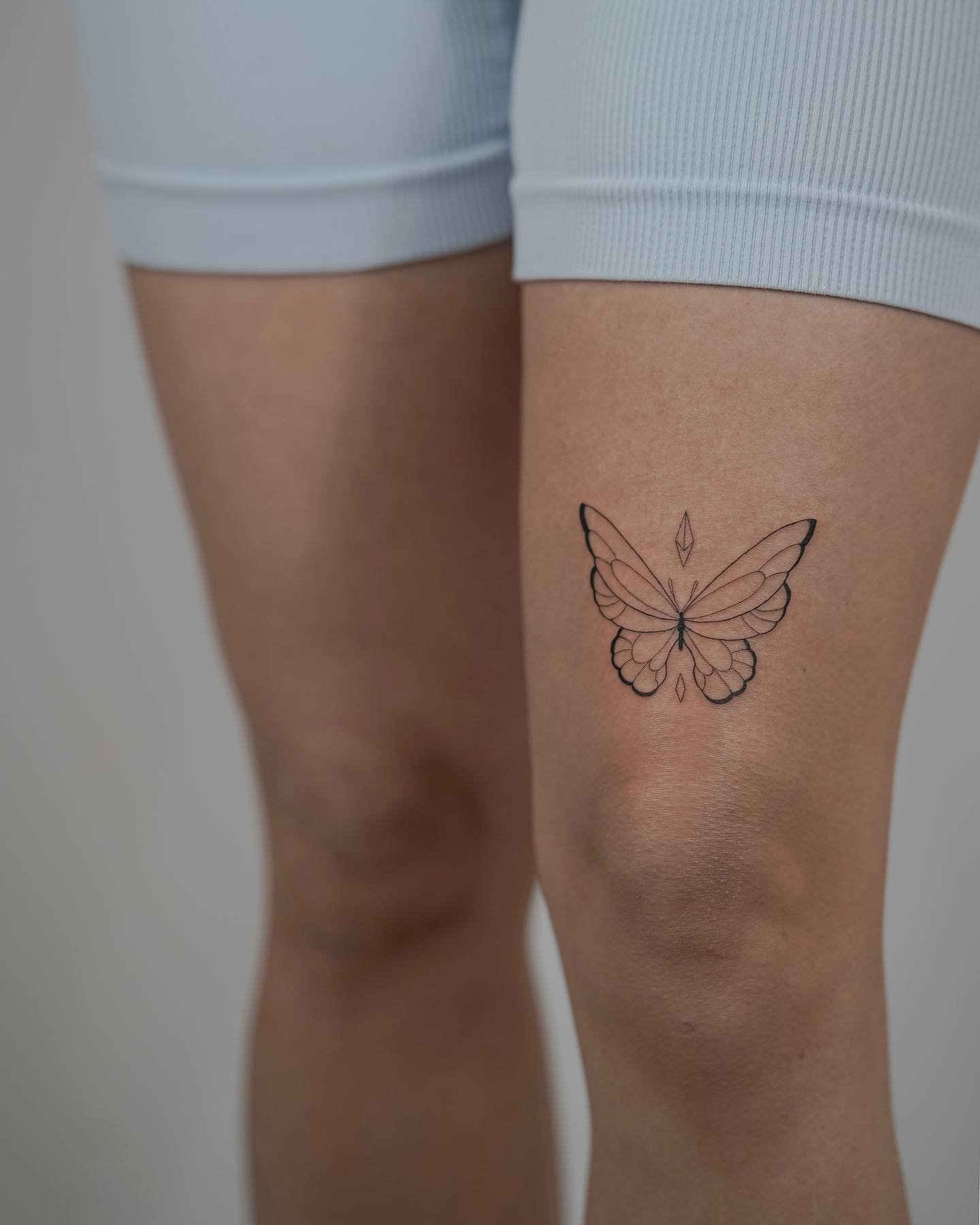 Tatuaje de mariposa en muslo, línea fina Sinkply Madrid