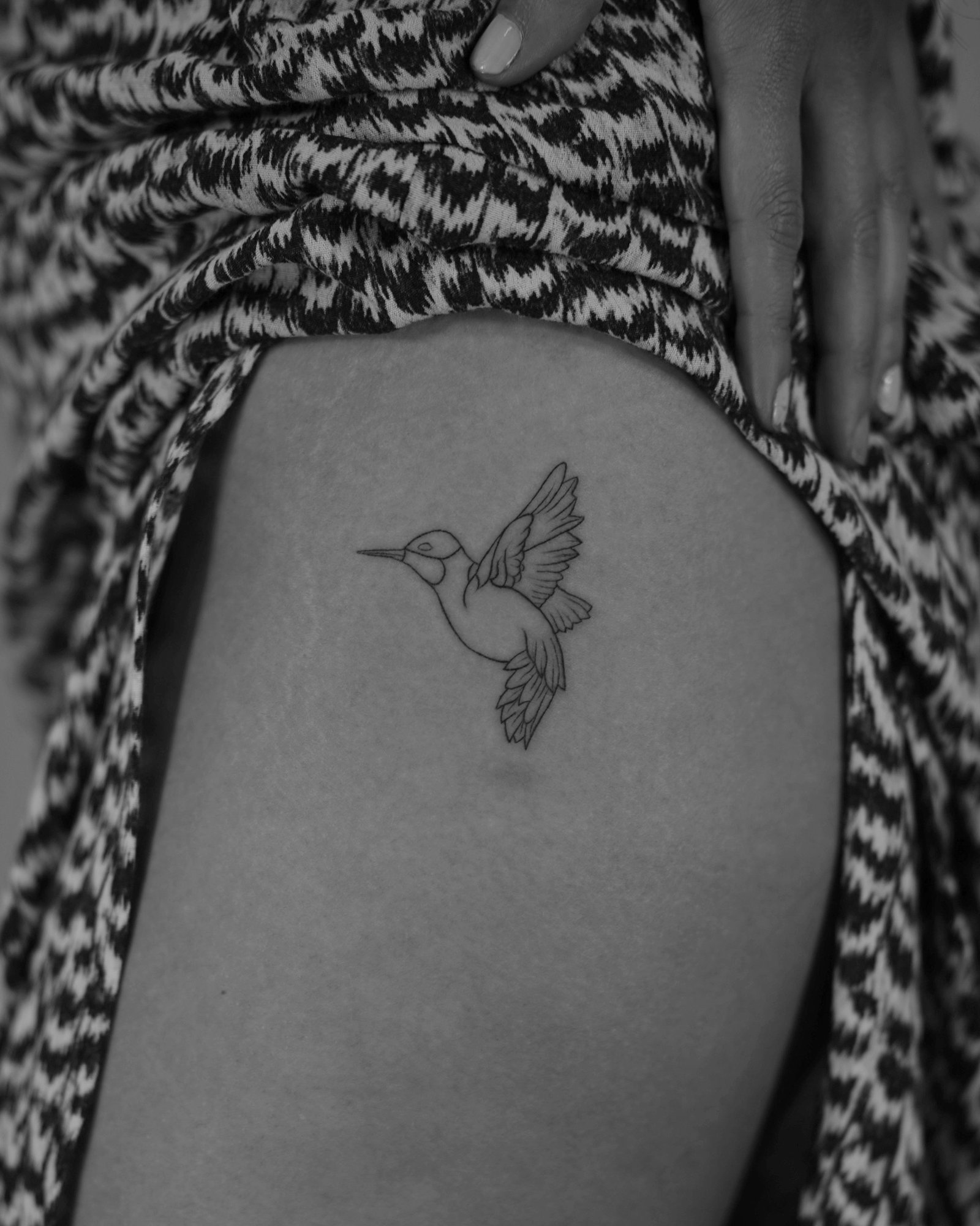 Tatuaje de colibri en vuelo lineal en costilla, línea fina