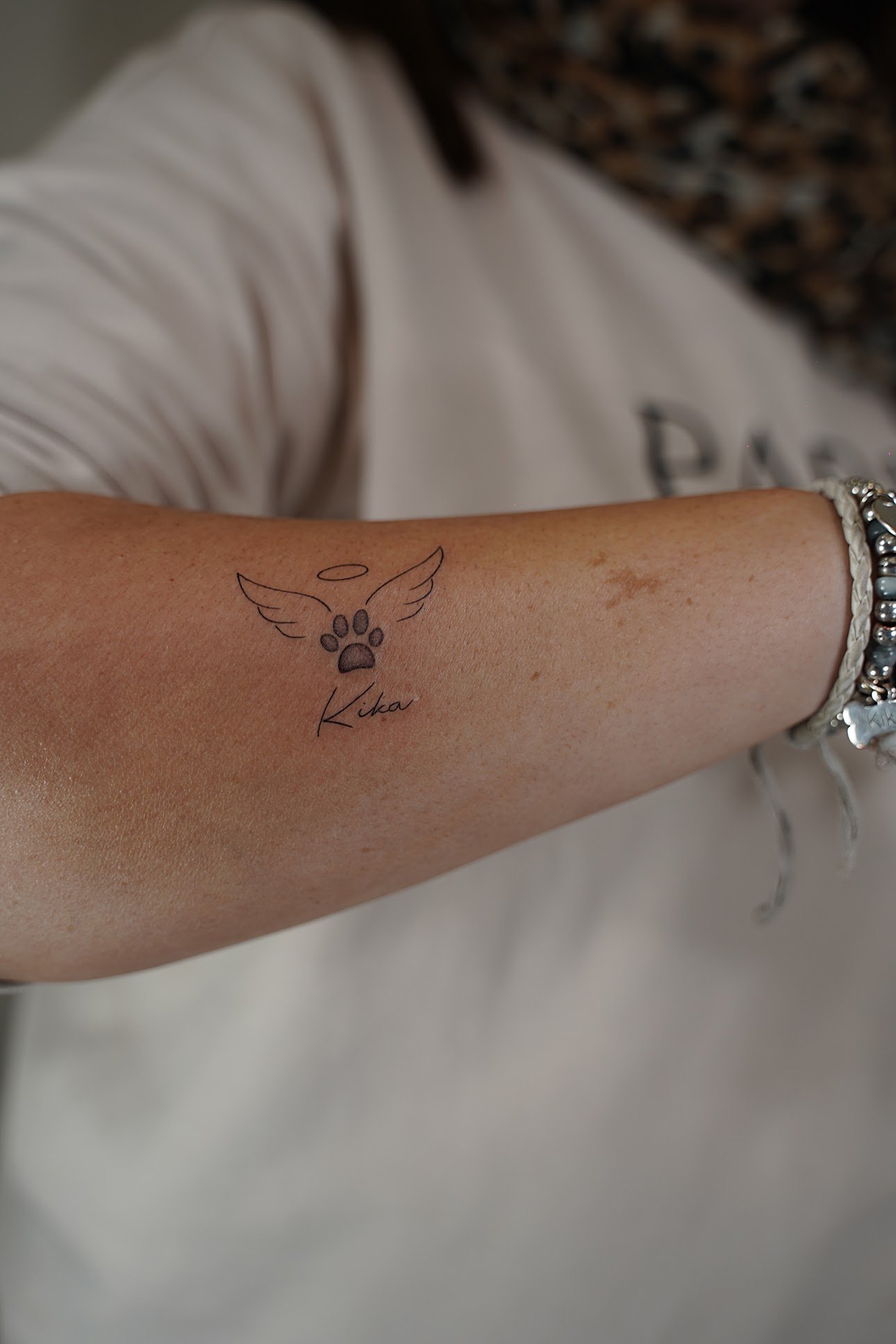 Tatuaje de huella alas angel nombre en antebrazo, línea fina