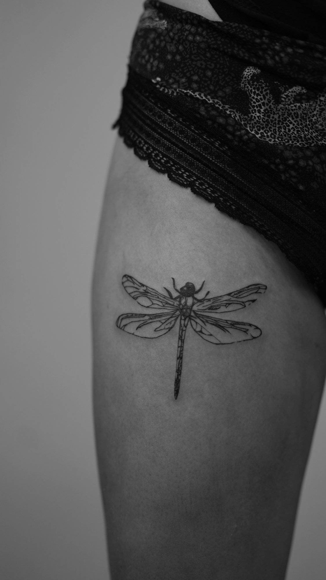 Tatuaje de libelula alas detalladas en muslo, línea fina