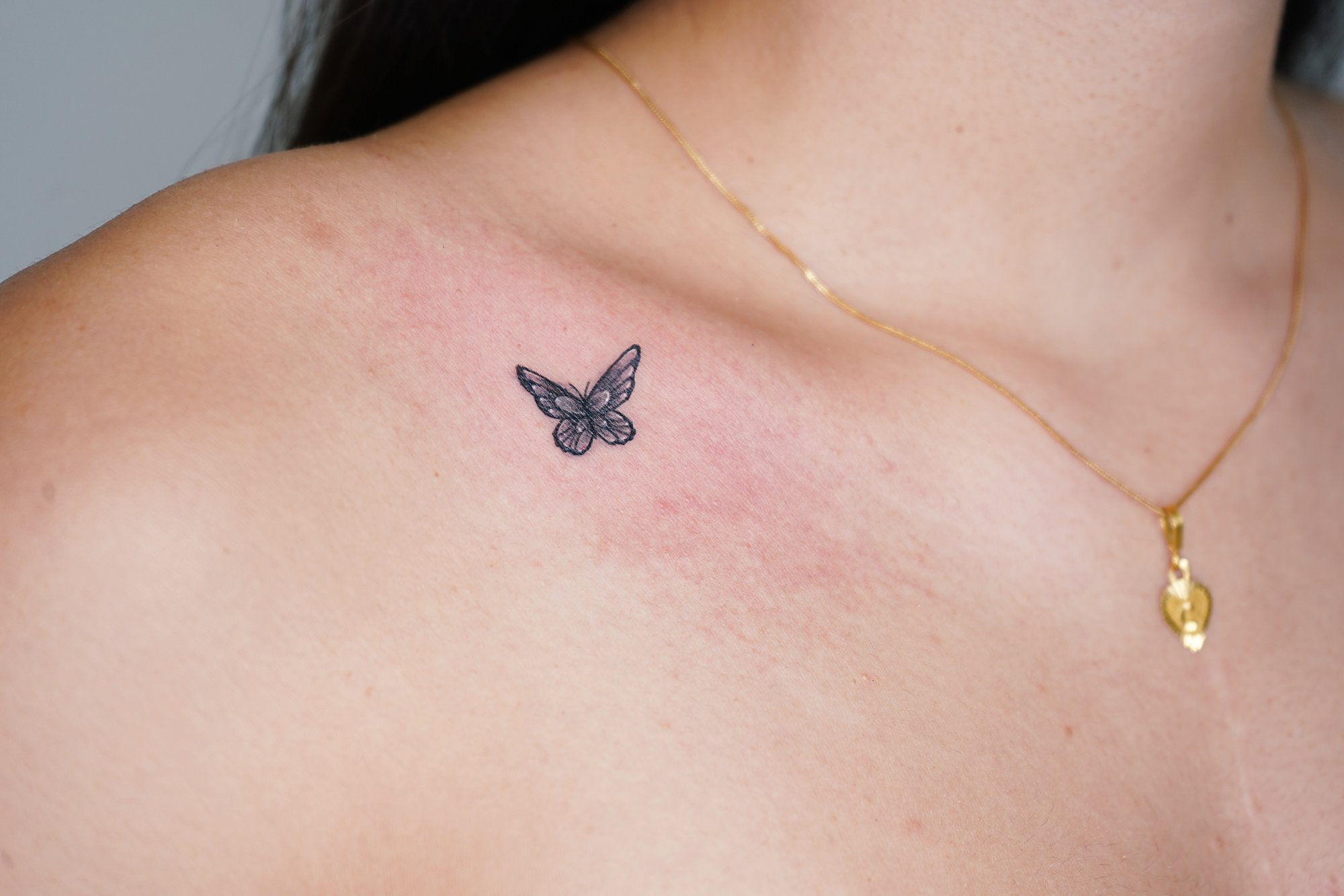 Tatuaje de mariposa en clavicula, línea fina