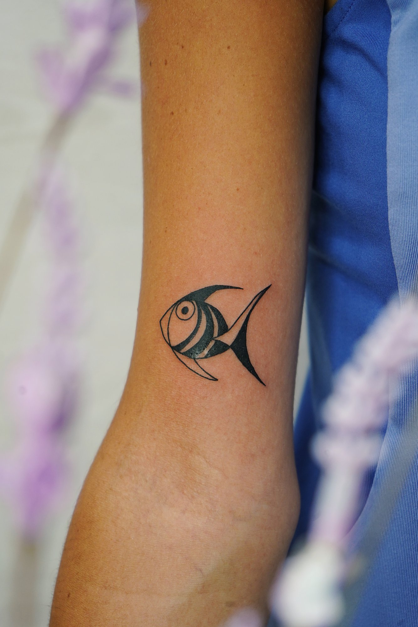 Tatuaje de pez en biceps, línea fina