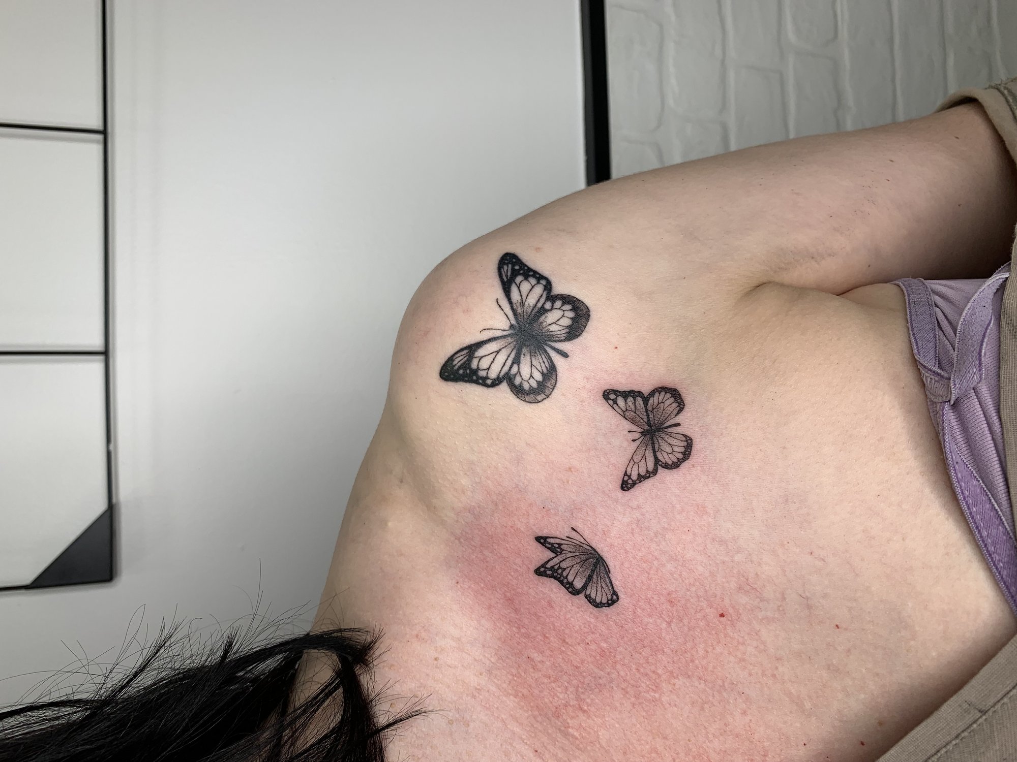 Tatuaje de tres mariposas volando en hombro, línea fina