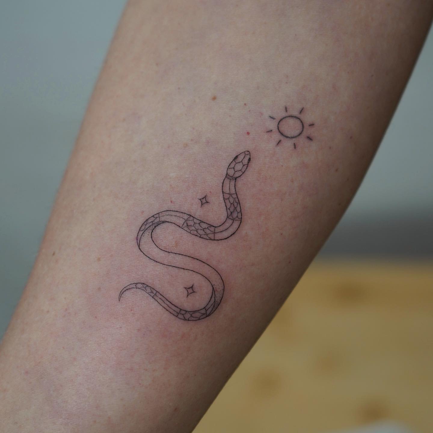Tatuaje de sol en antebrazo, línea fina Sinkply Madrid