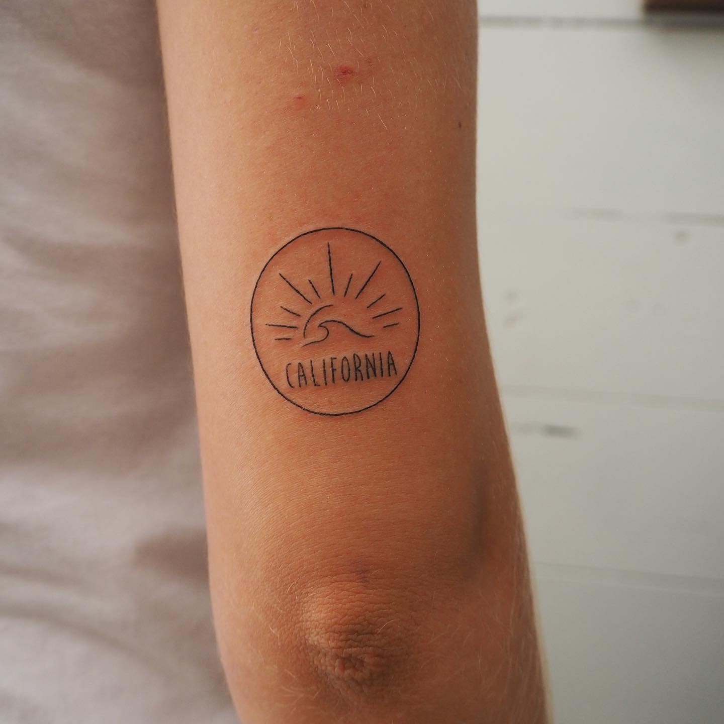 Tatuaje de sol en antebrazo, línea fina Sinkply Madrid