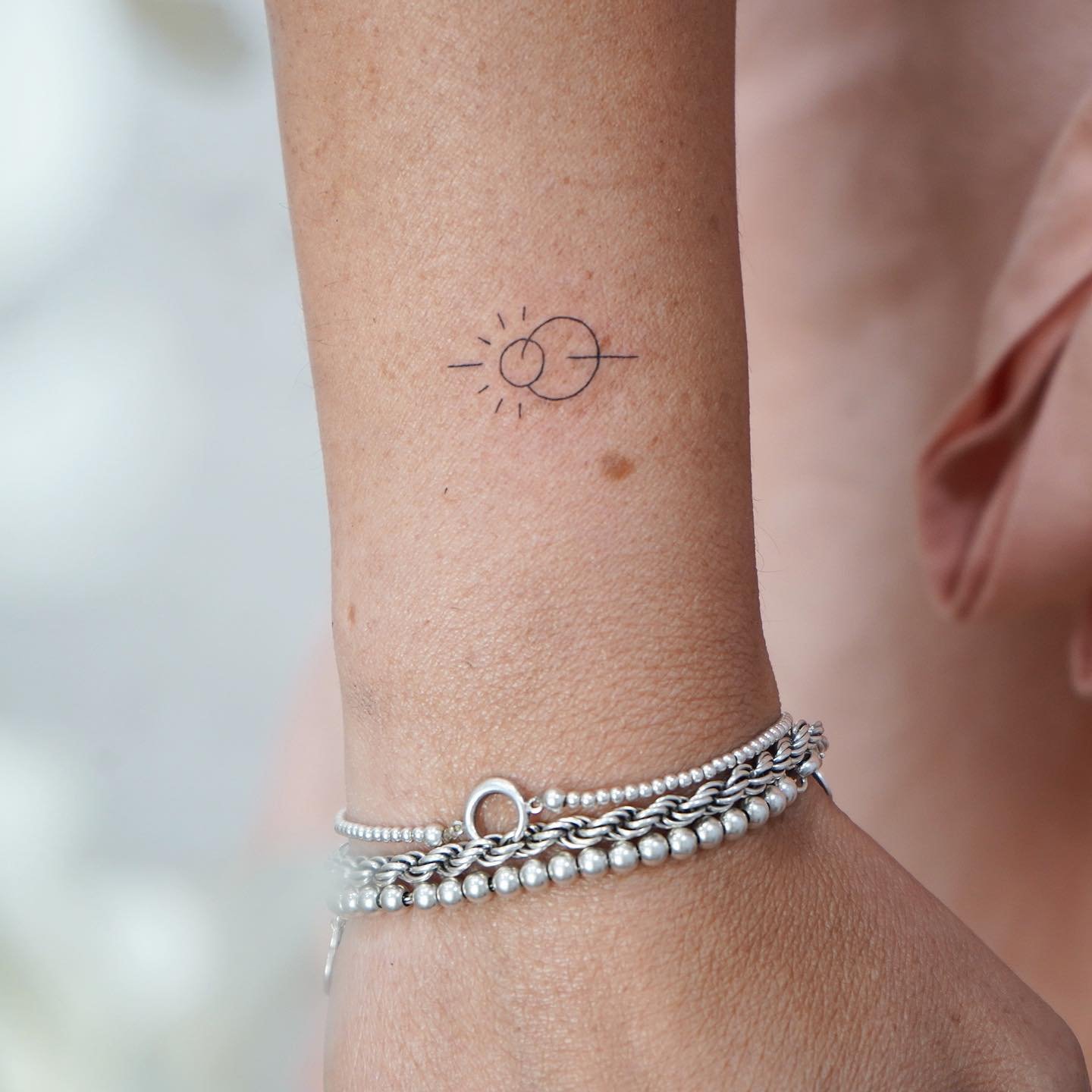 Tatuaje de sol en antebrazo, línea fina Sinkply Madrid