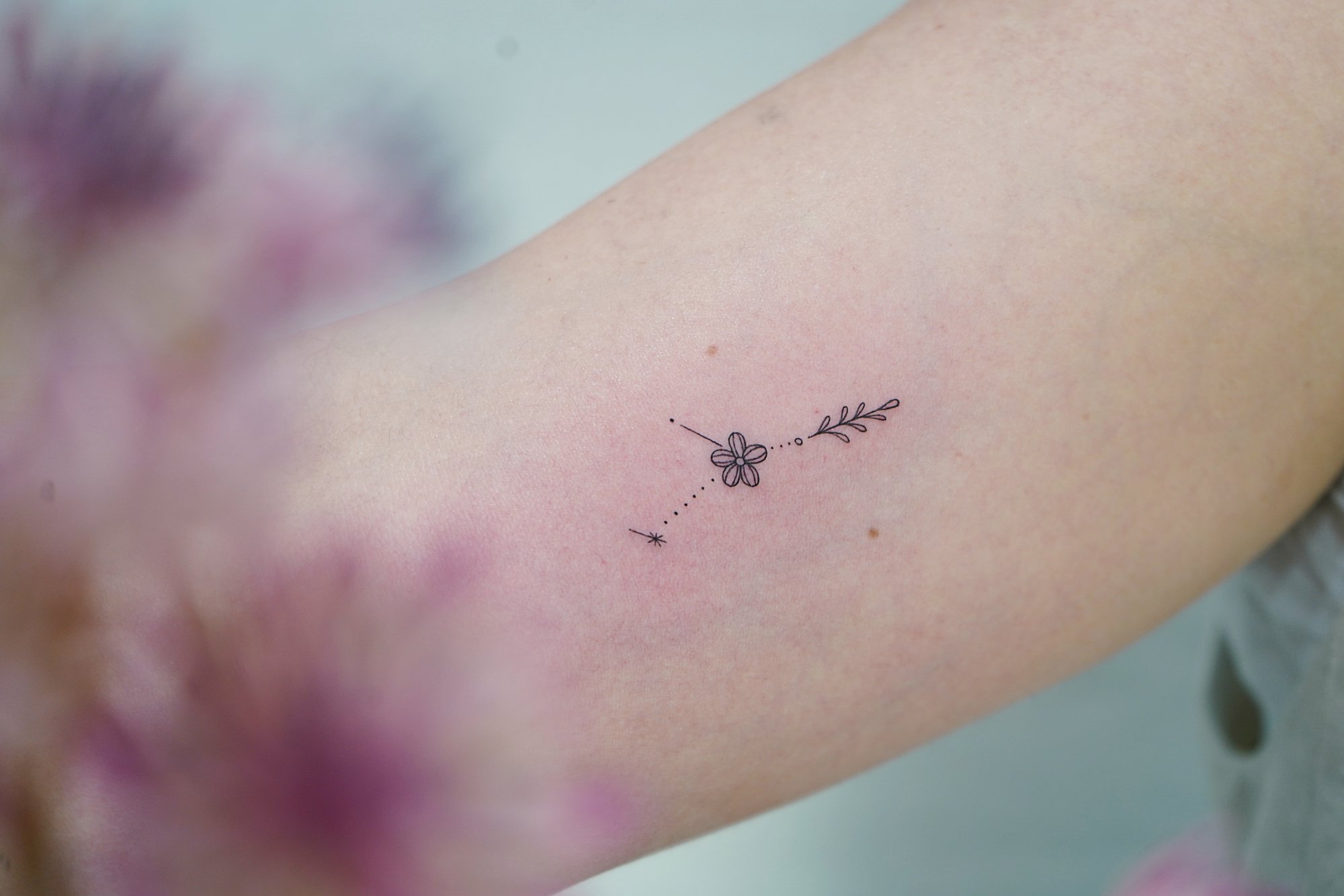 Tatuaje de constelacion flor en biceps, línea fina
