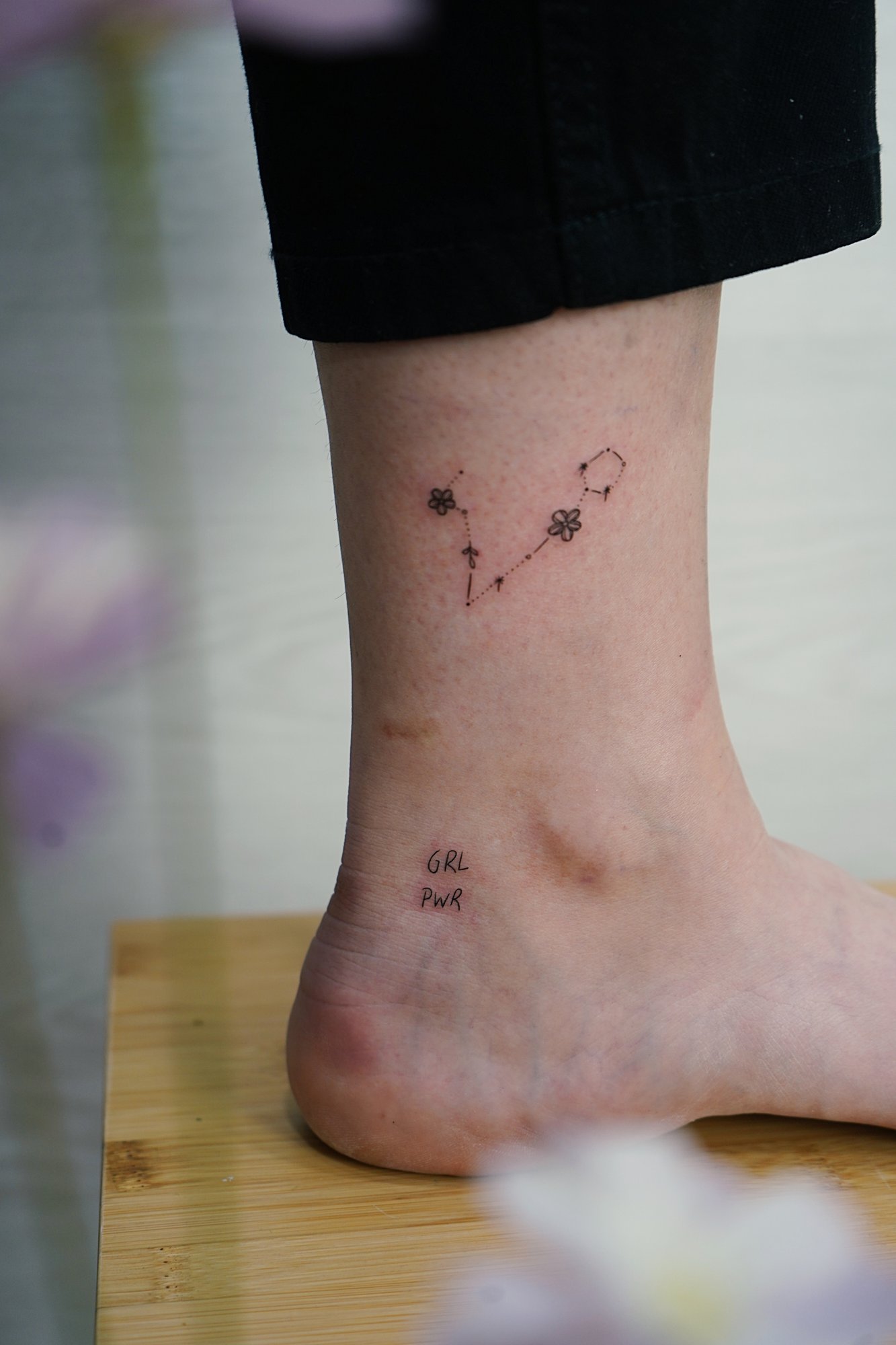 Tatuaje de constelacion girl power en tobillo, línea fina