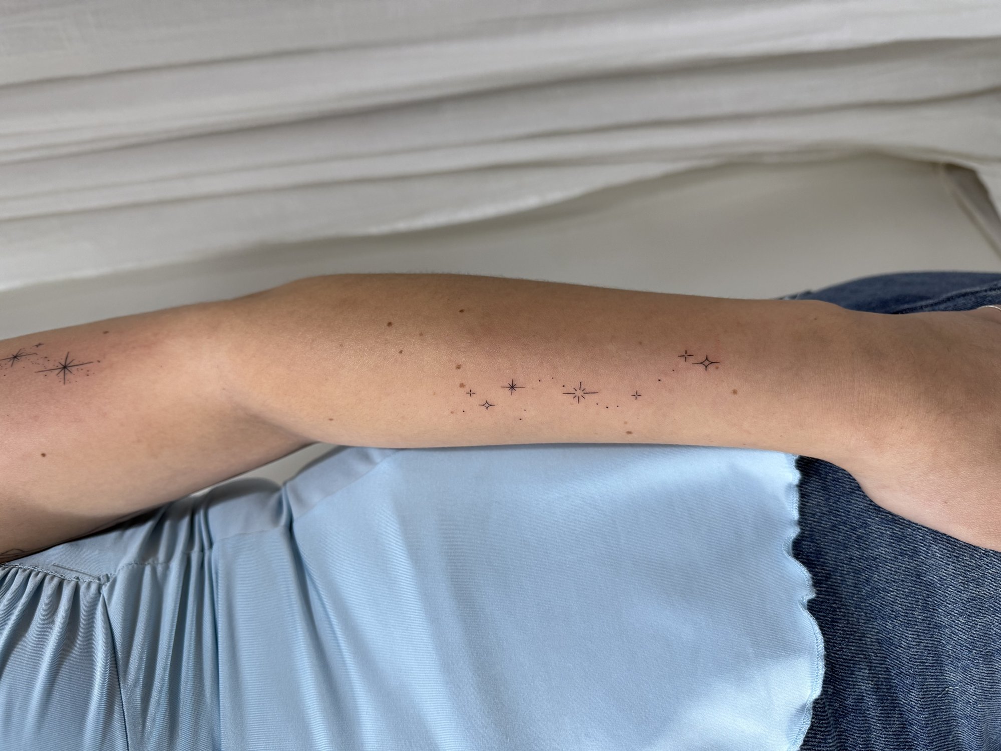 Tatuaje de destellos composicion en antebrazo, línea fina