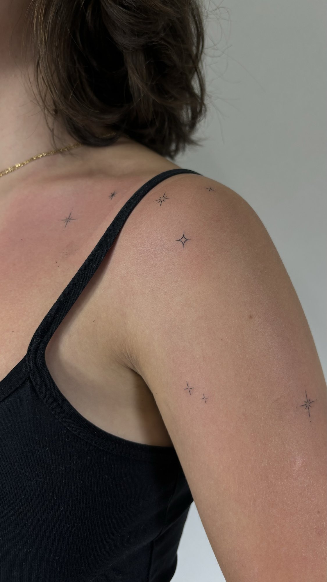 Tatuaje de estrellas brillantes dispersas en hombro, línea fina