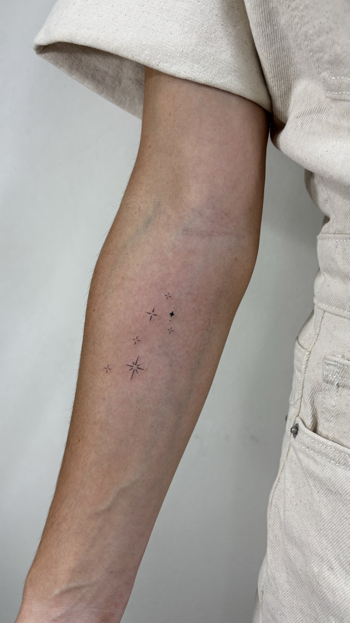 Tatuaje de estrellas brillantes varias ta en antebrazo, línea fina