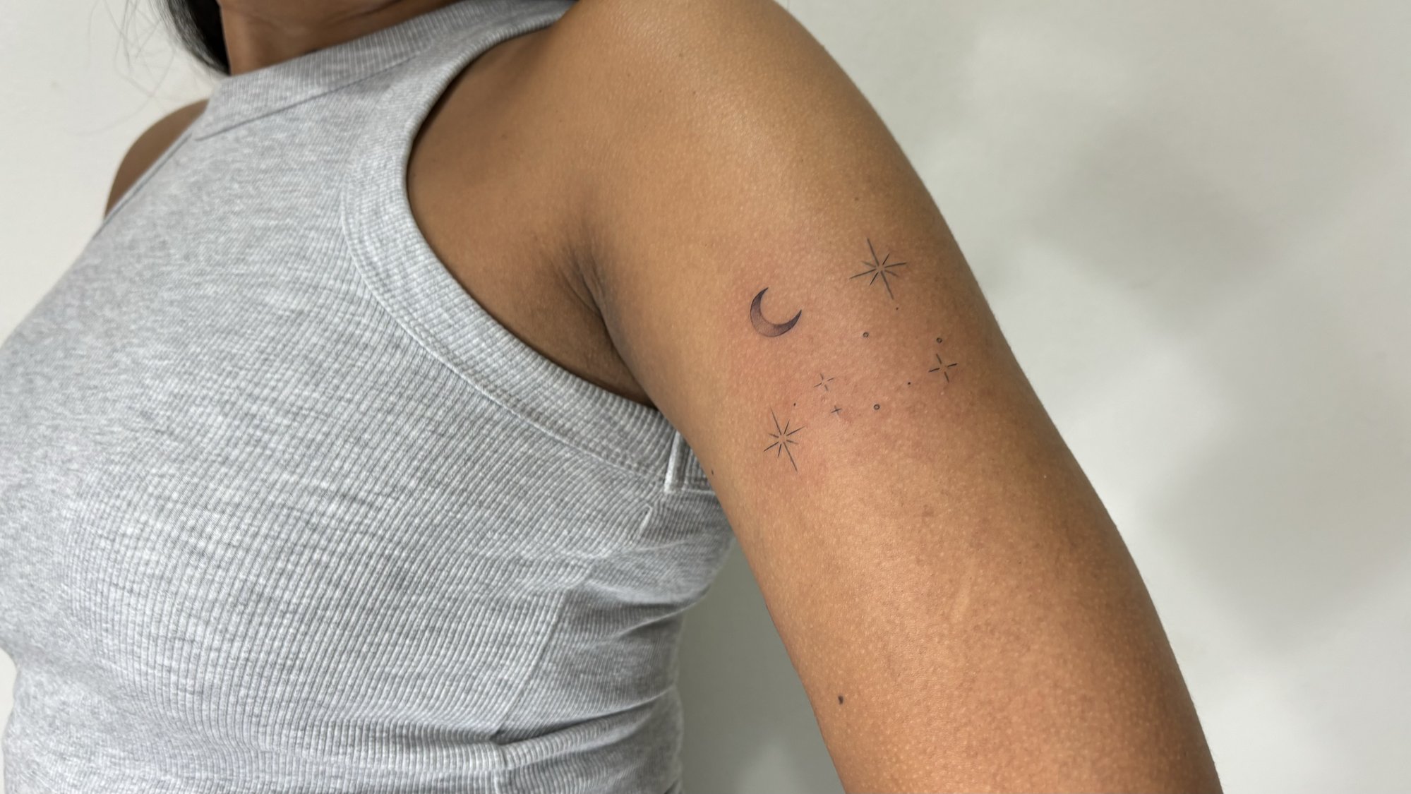 Tatuaje de luna y estrellas minimalistas en brazo, línea fina