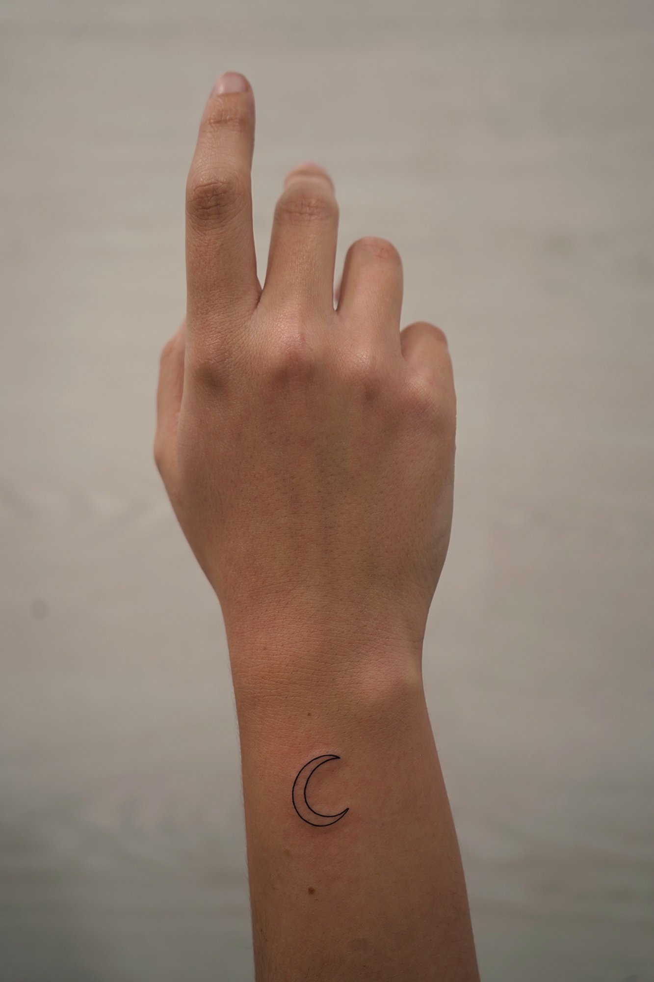 Tatuaje de luna en muneca, línea fina