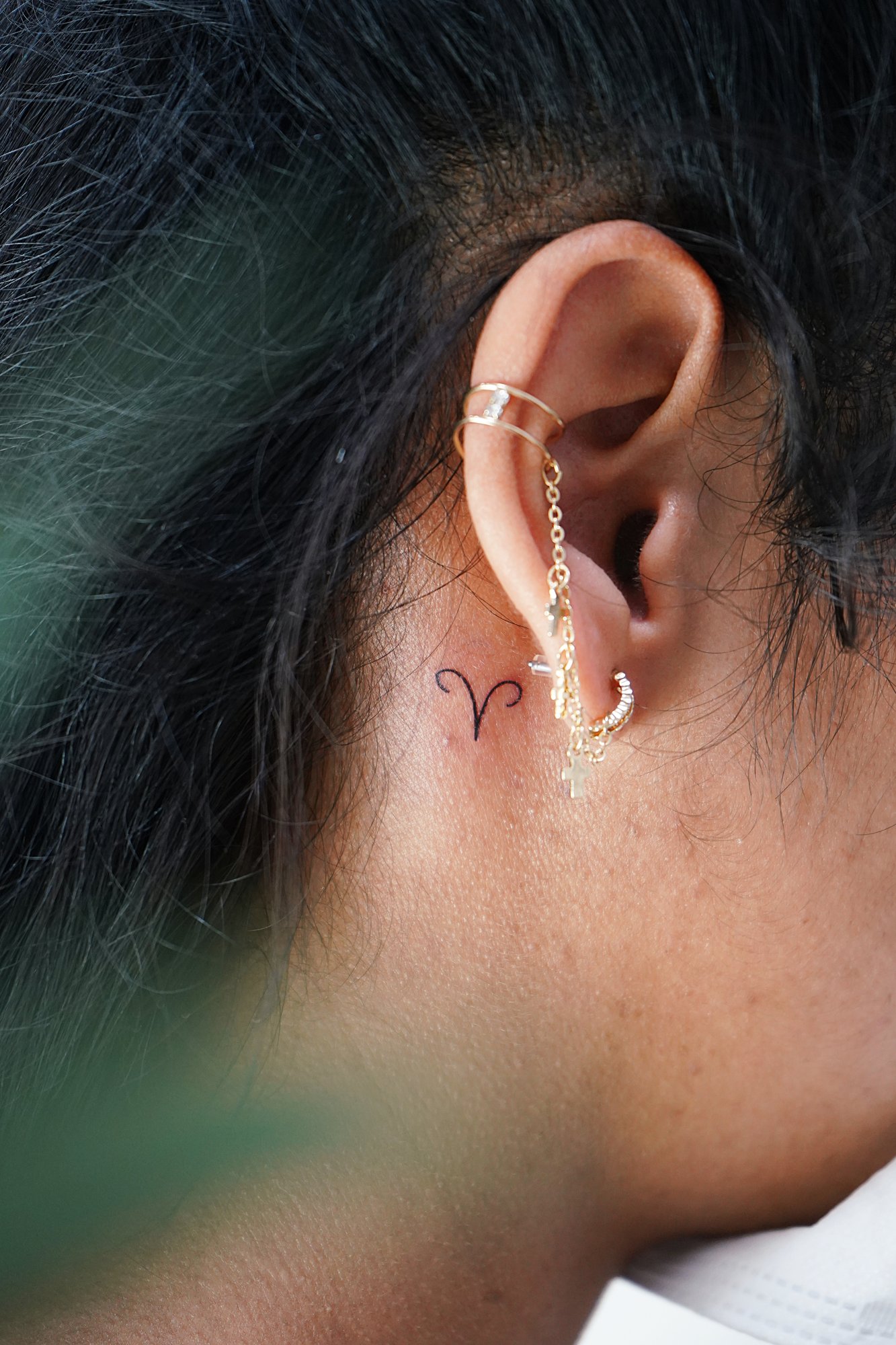 Tatuaje de simbolo zodiaco en detras oreja, línea fina