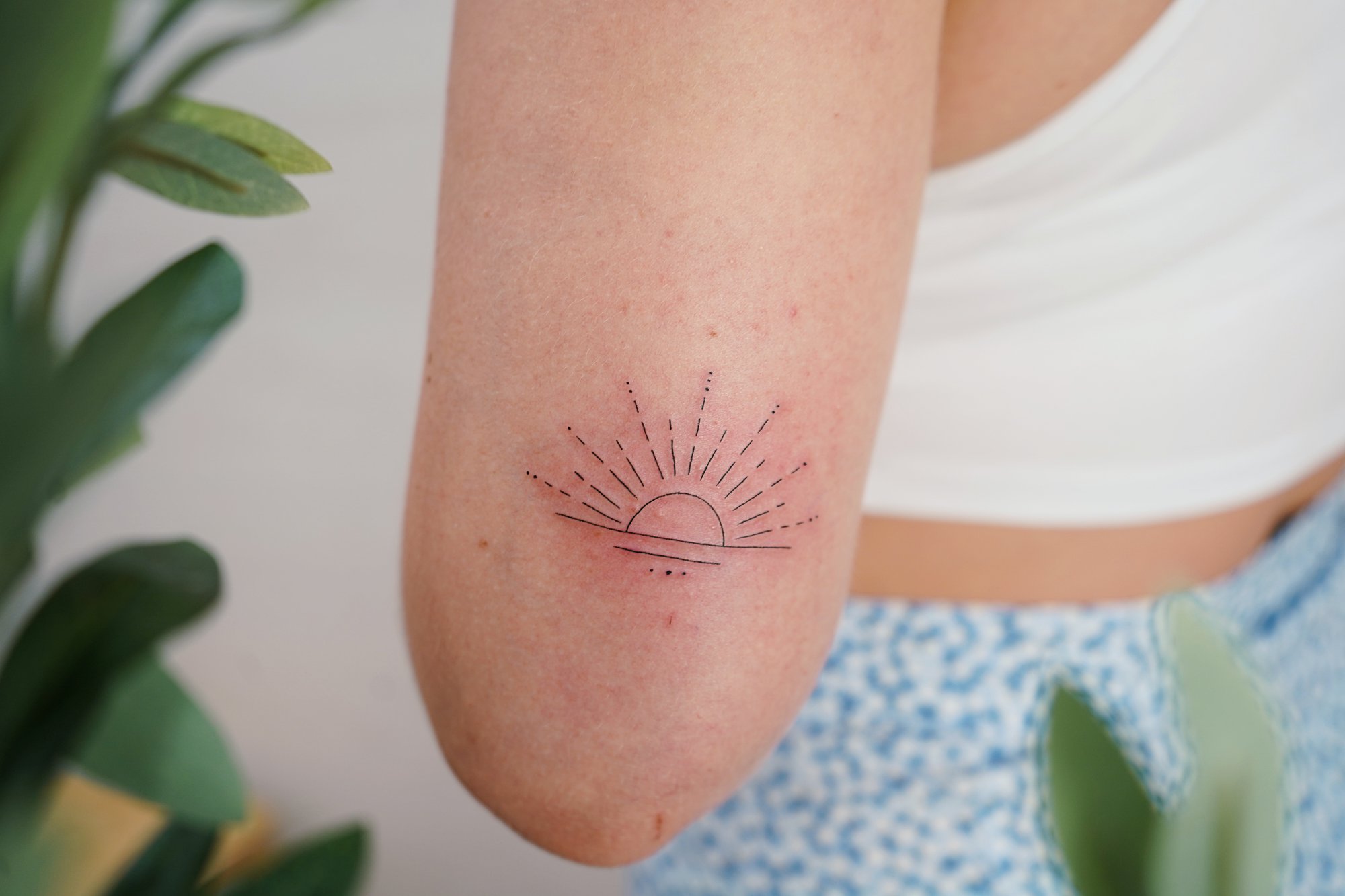 Tatuaje de sol en codo, línea fina