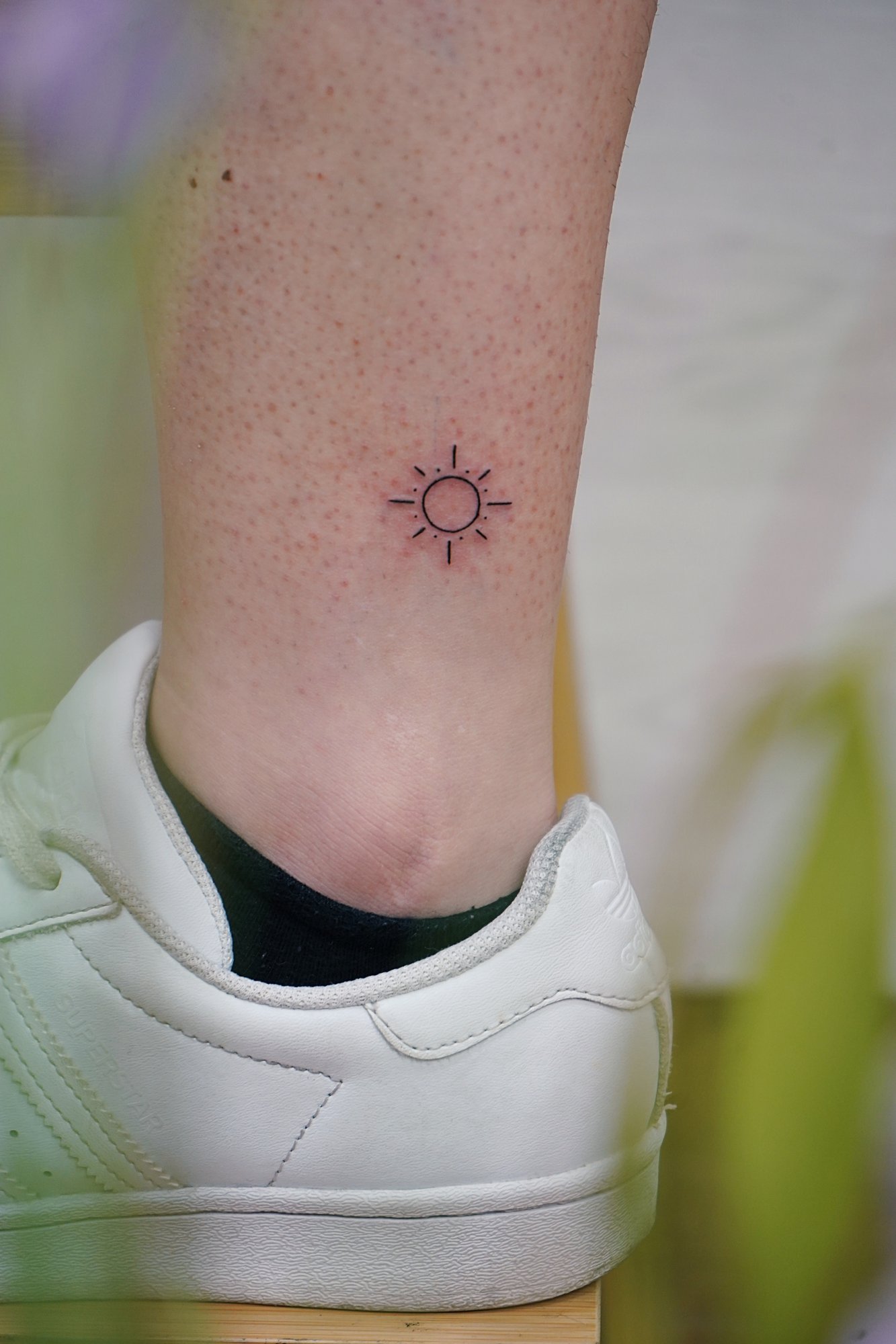 Tatuaje de sol en tobillo, línea fina