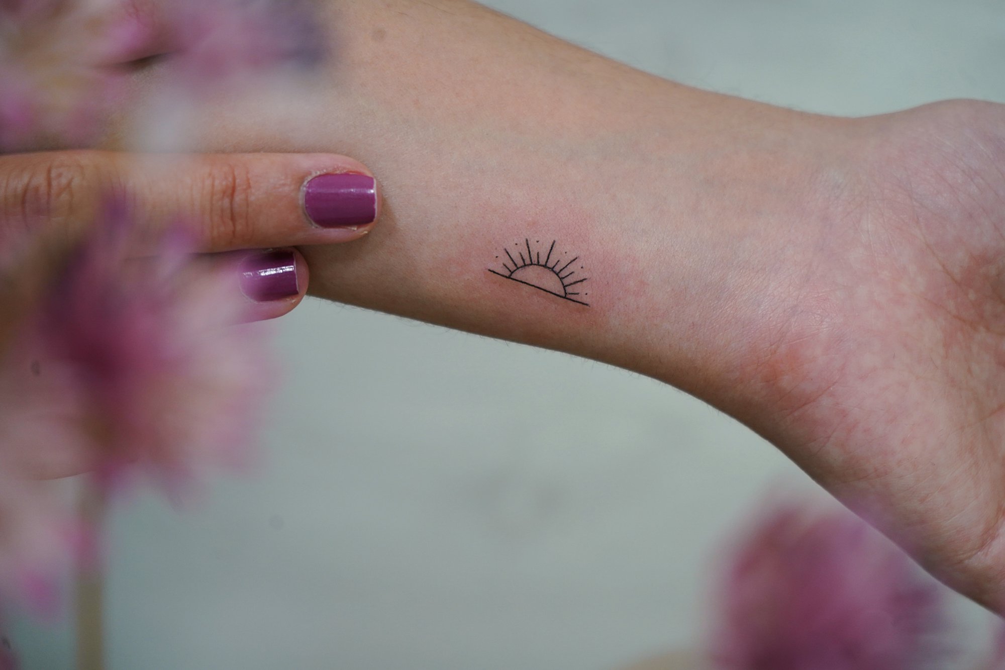 Tatuaje de soles en muneca, línea fina