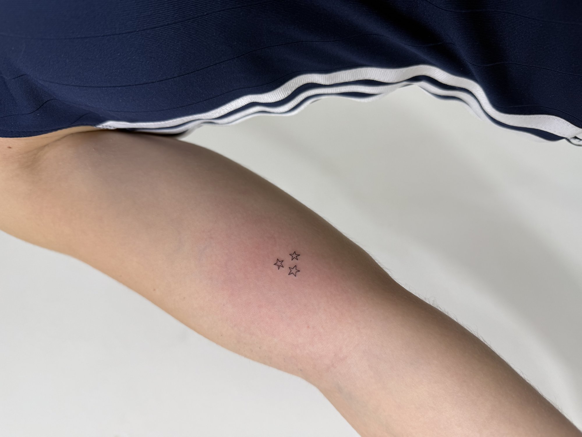 Tatuaje de tres estrellas pequenas outlin en brazo, línea fina