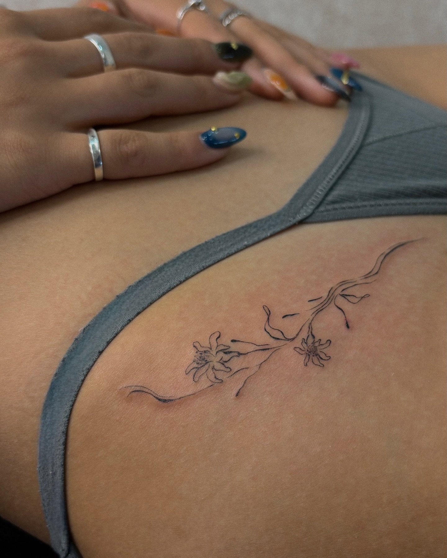 Tatuaje de flor en costilla, línea fina Sinkply Madrid