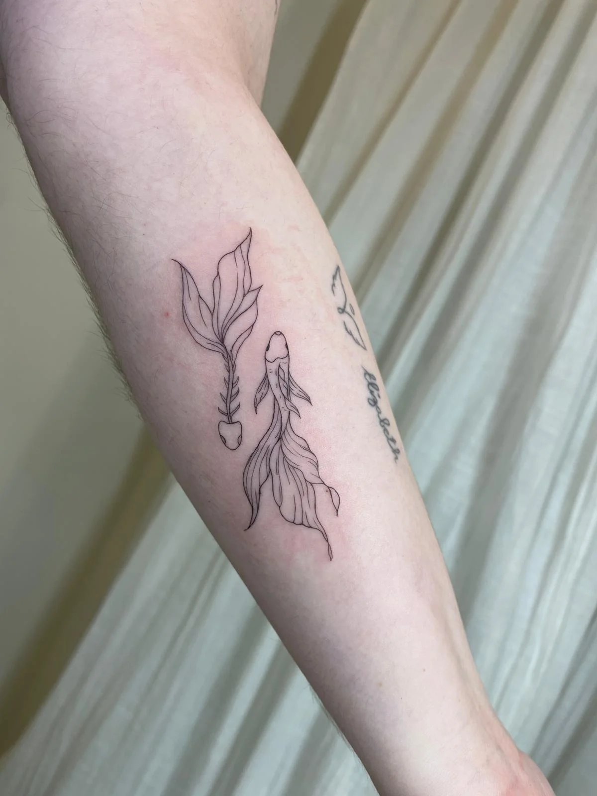 Tatuaje floral flecha con hojas botanicas antebrazo