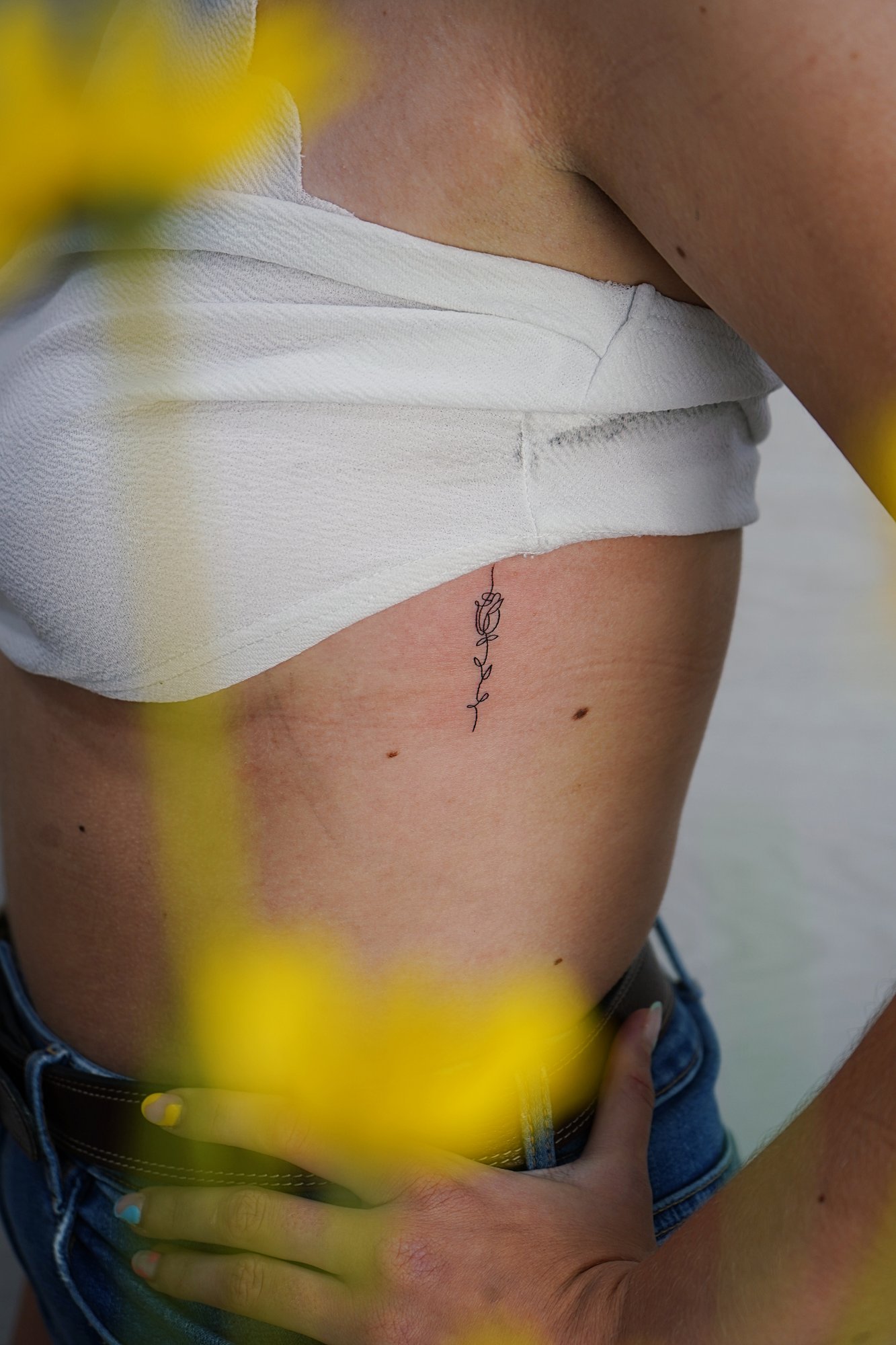 Tatuaje de flor en costilla, línea fina