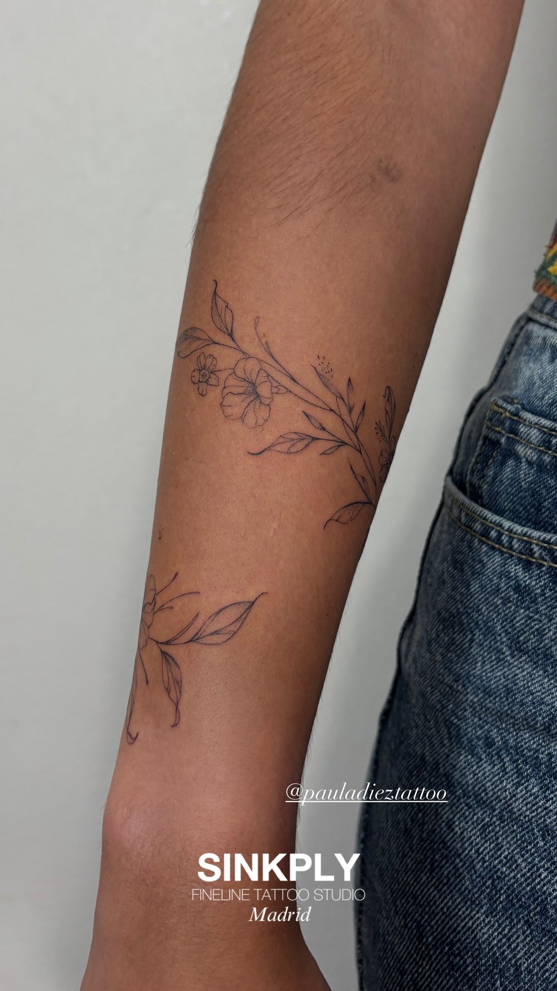 Tatuaje de flores hojas ramas enredadera en antebrazo, línea fina