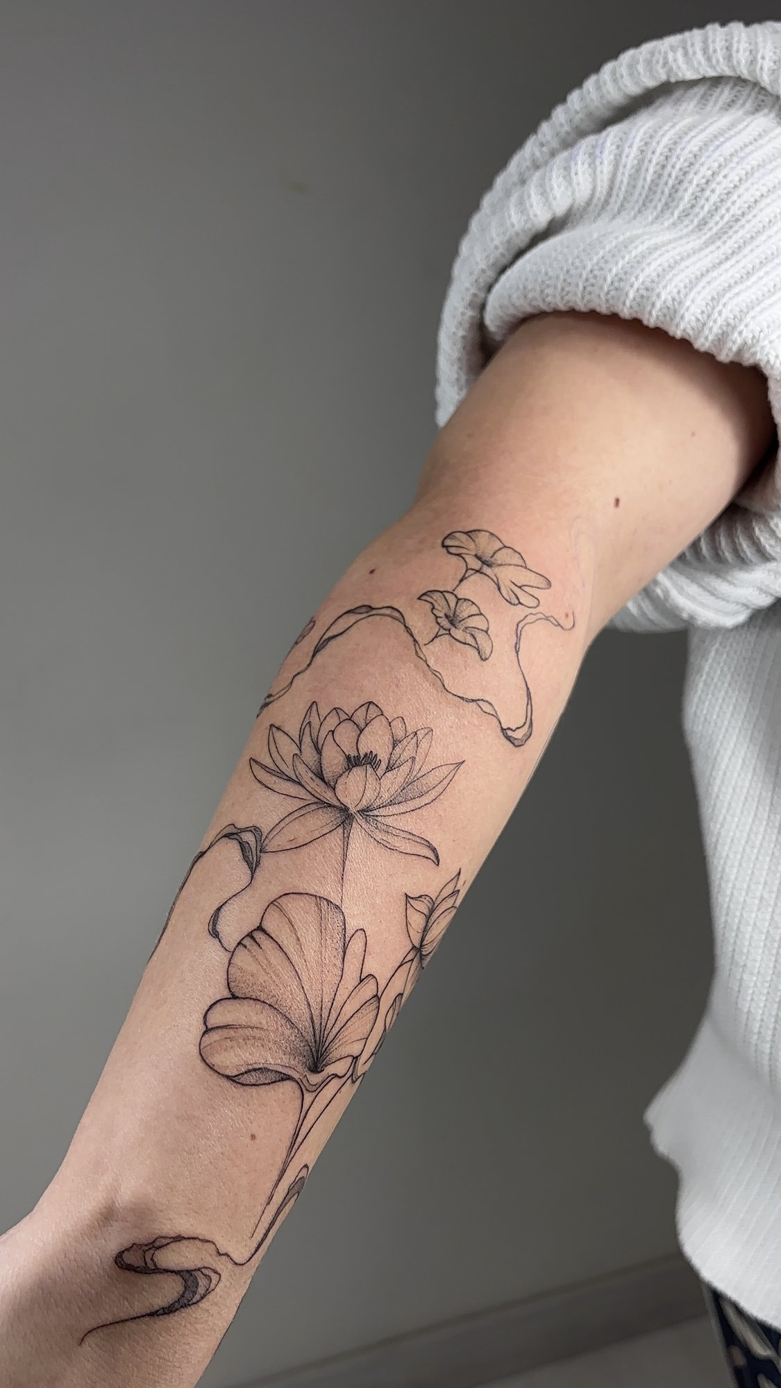 Tatuaje de flores variadas estilo lineal en antebrazo, línea fina