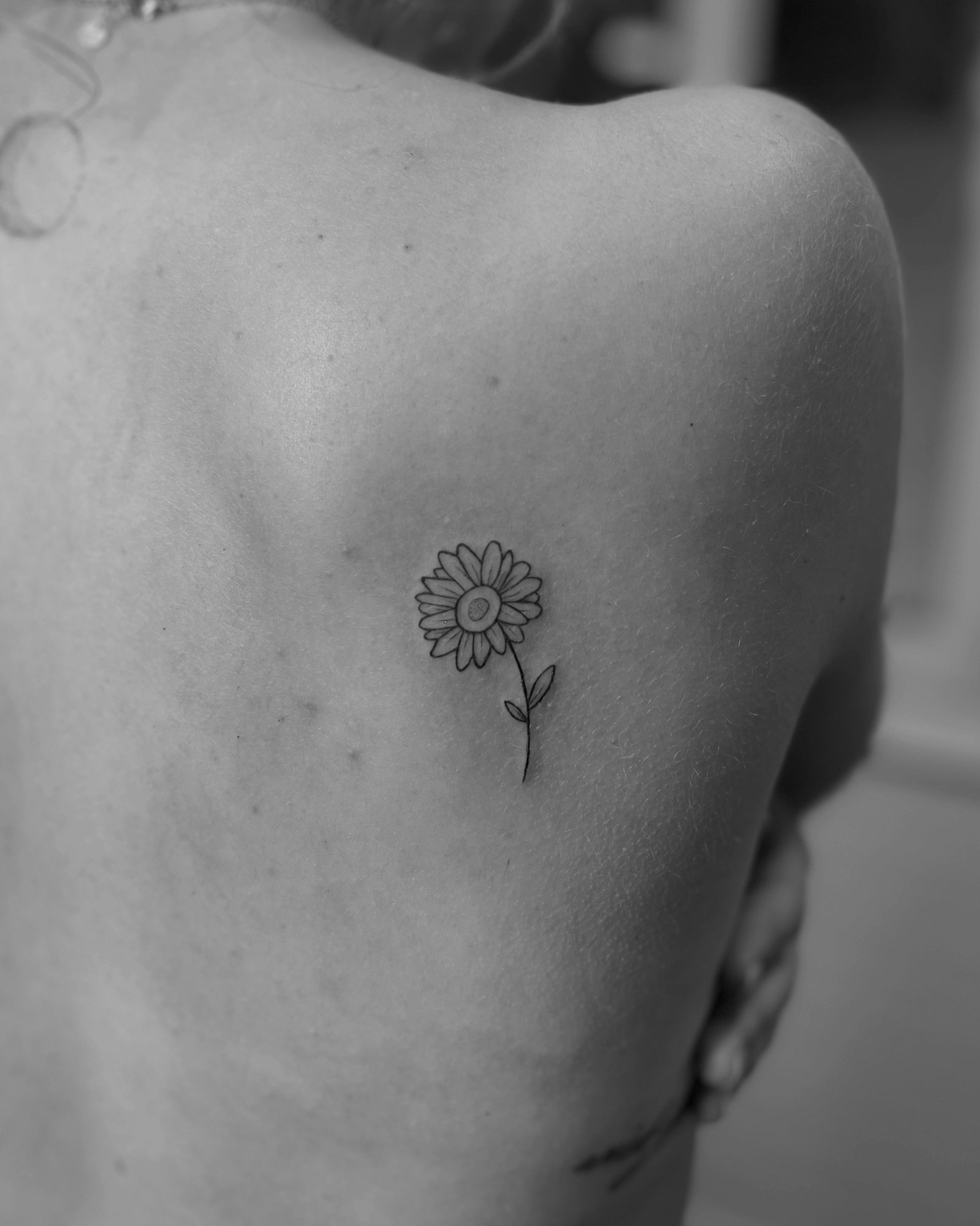 Tatuaje de girasol pequeno minimalista li en espalda, línea fina