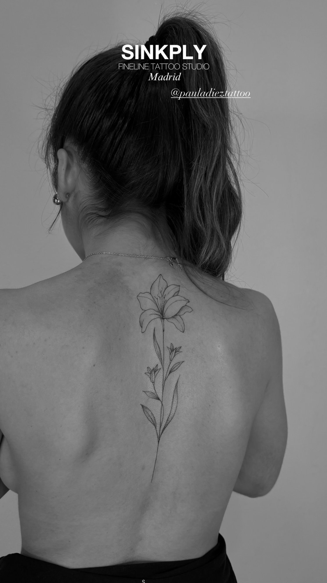 Tatuaje de lirio fineline tallo largo en espalda, línea fina