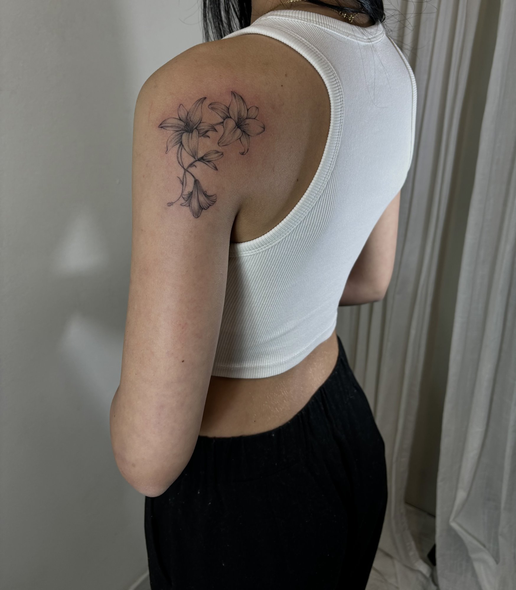 Tatuaje de lirios delicados fineline en hombro, línea fina