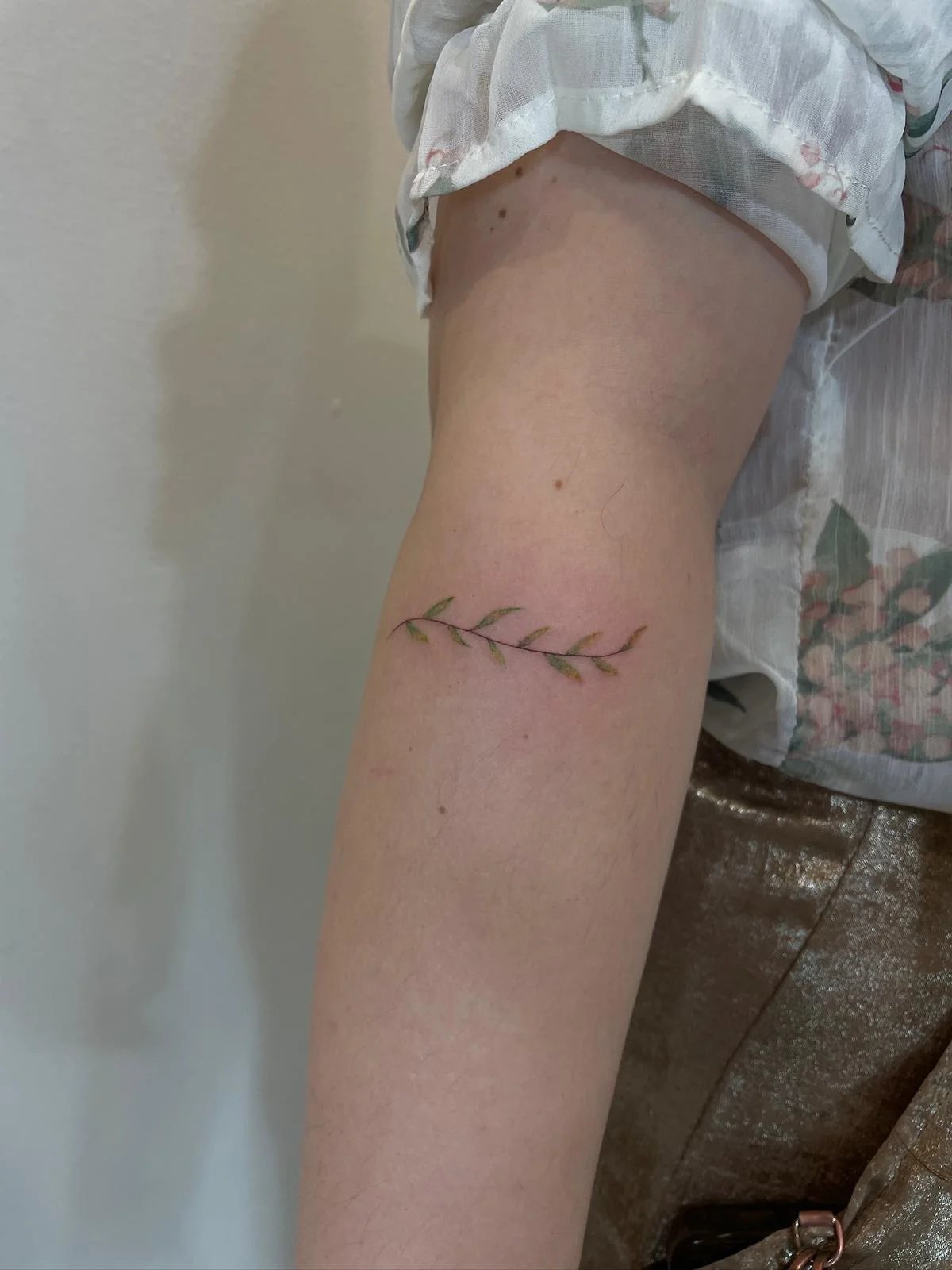 Tatuaje floral rama con hojas verdes antebrazo