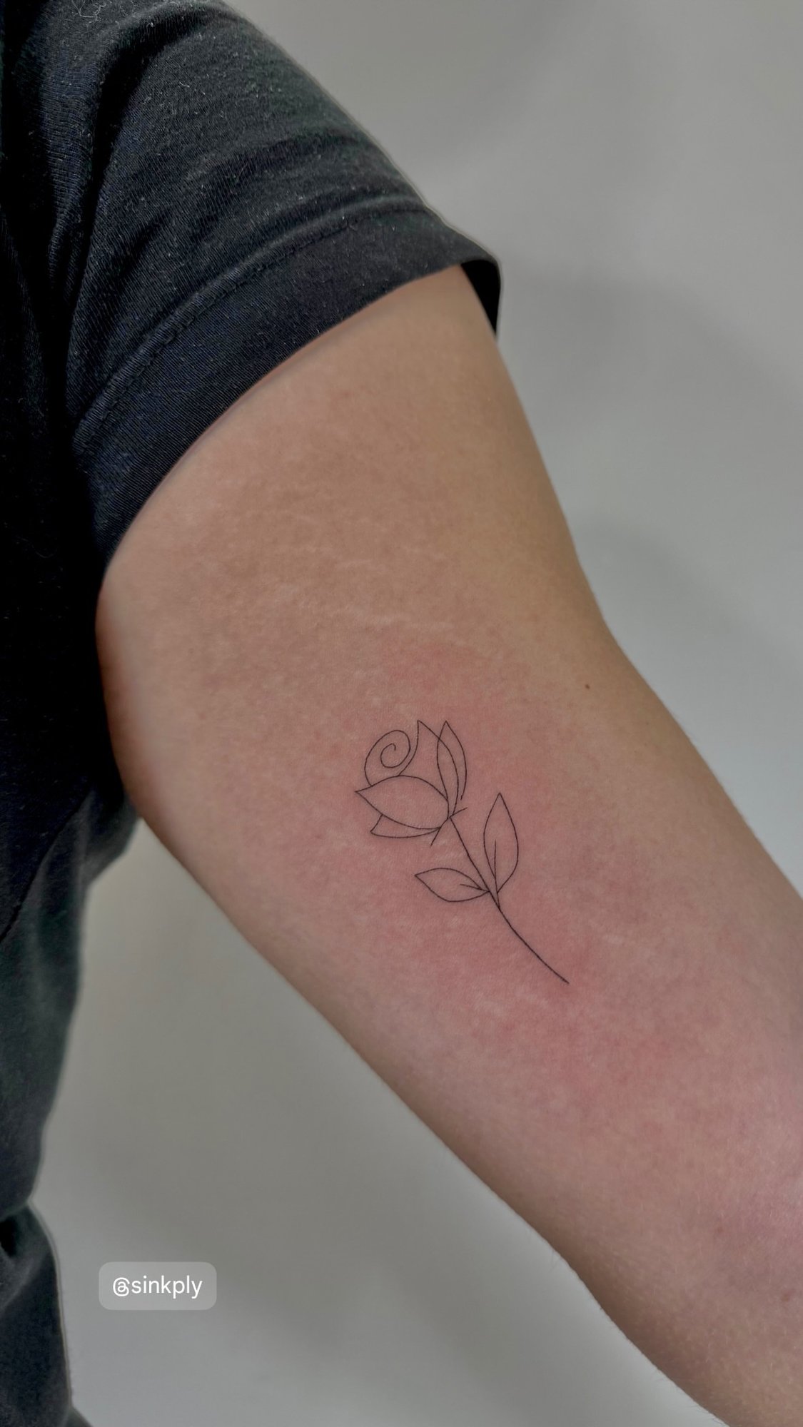 Tatuaje de rosa minimalista linea fina en brazo, línea fina