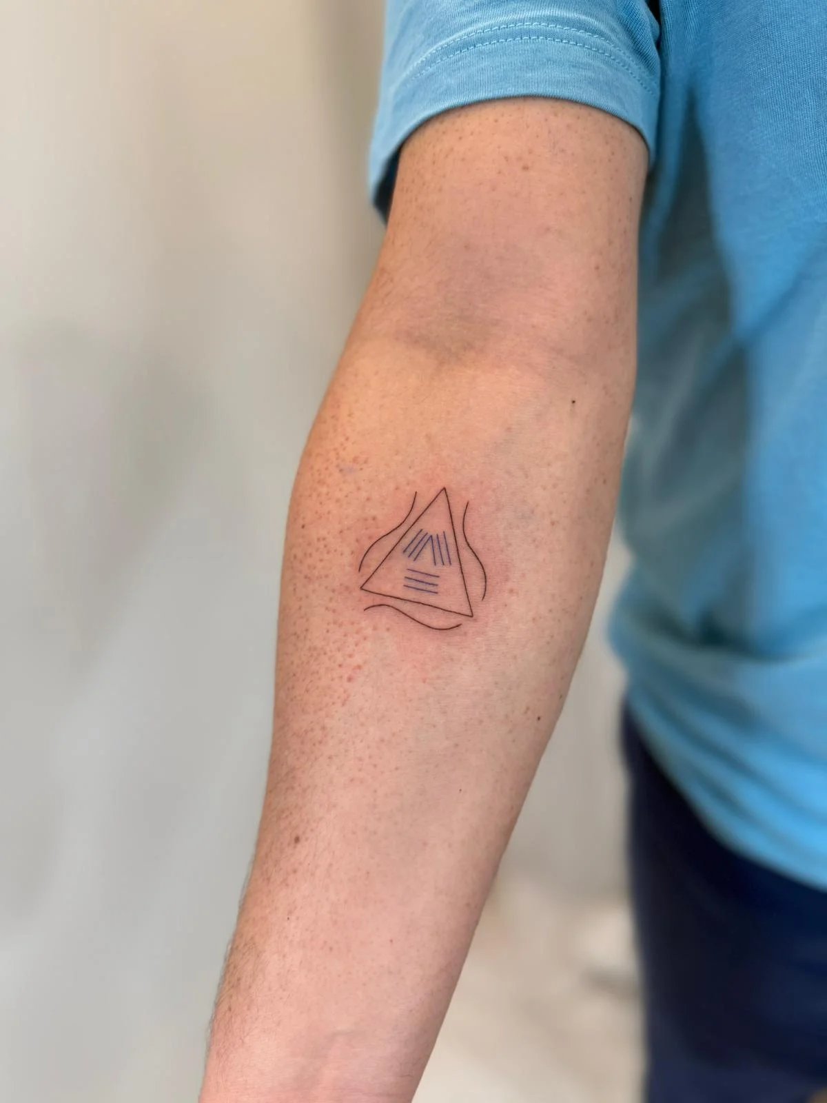 Tatuaje geometrico triangulo con lineas internas antebrazo