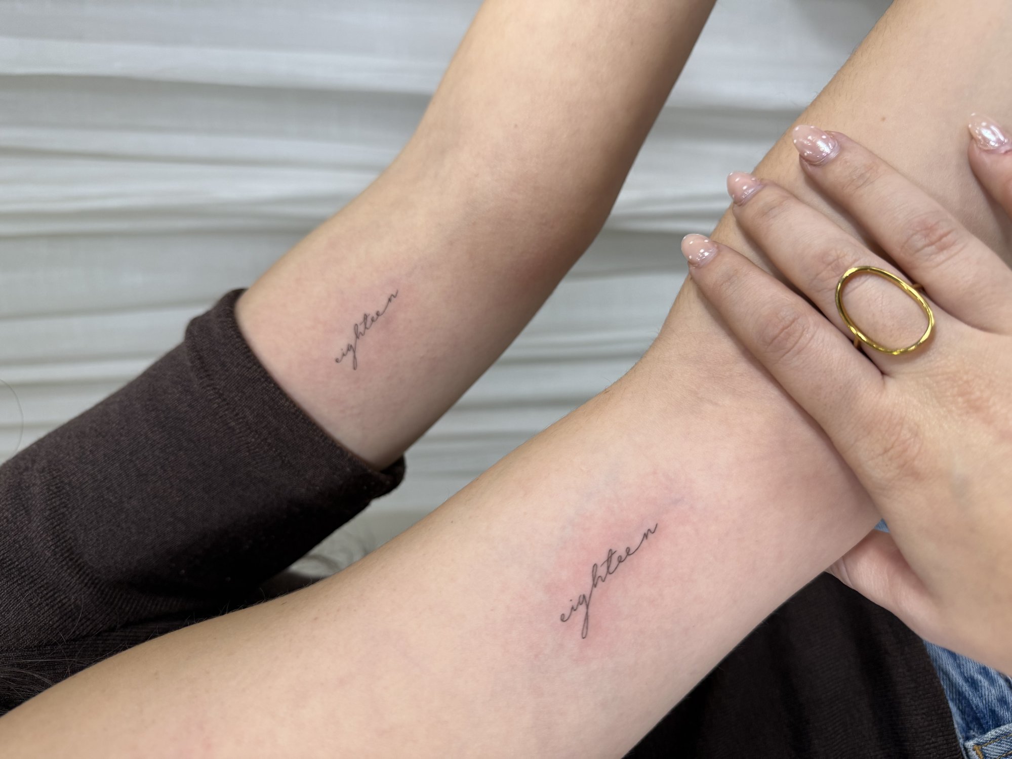Tatuaje de eighteen caligrafia cursiva ma en antebrazo, línea fina